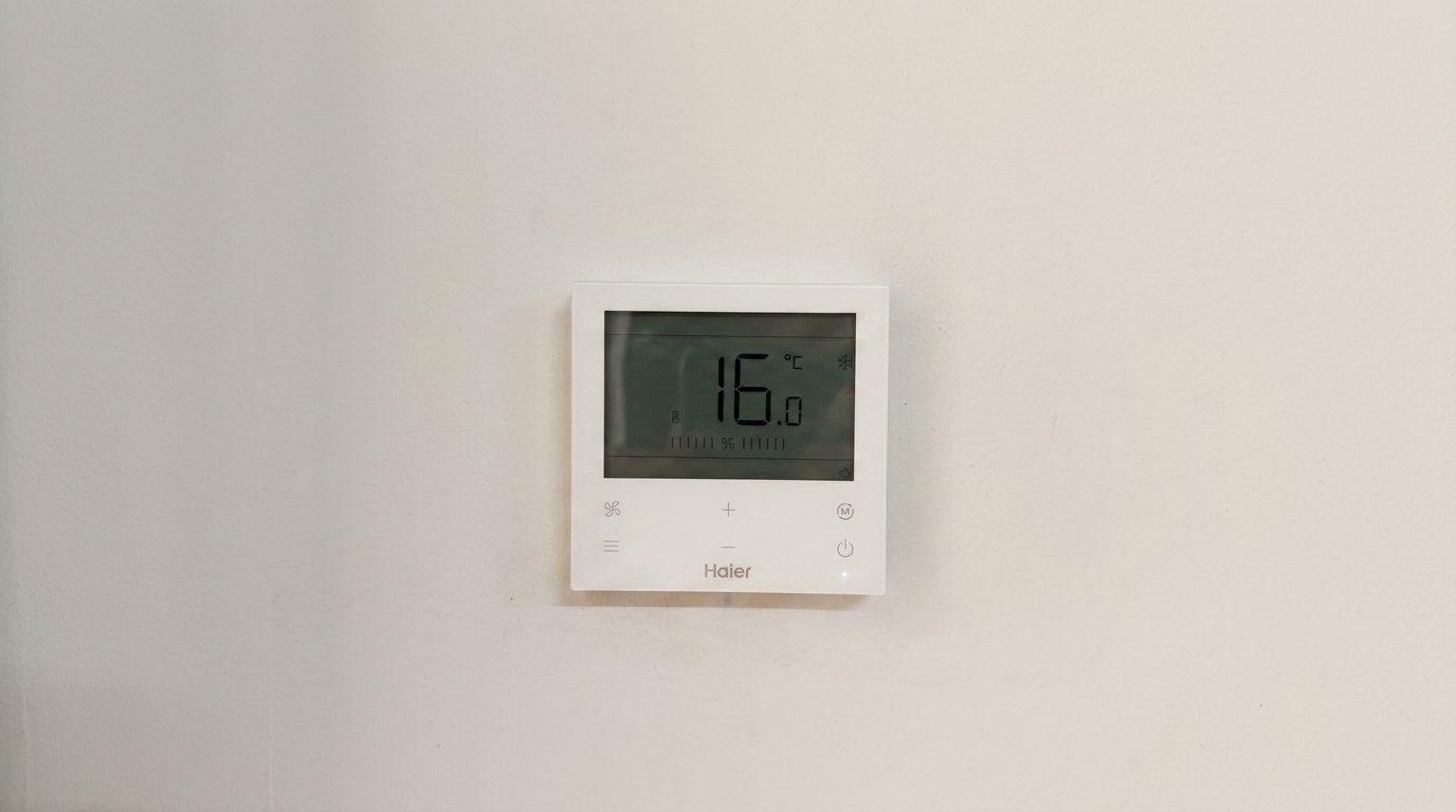 Weisser Haier-Raumthermostat an der Wand des Okaidi-Stores