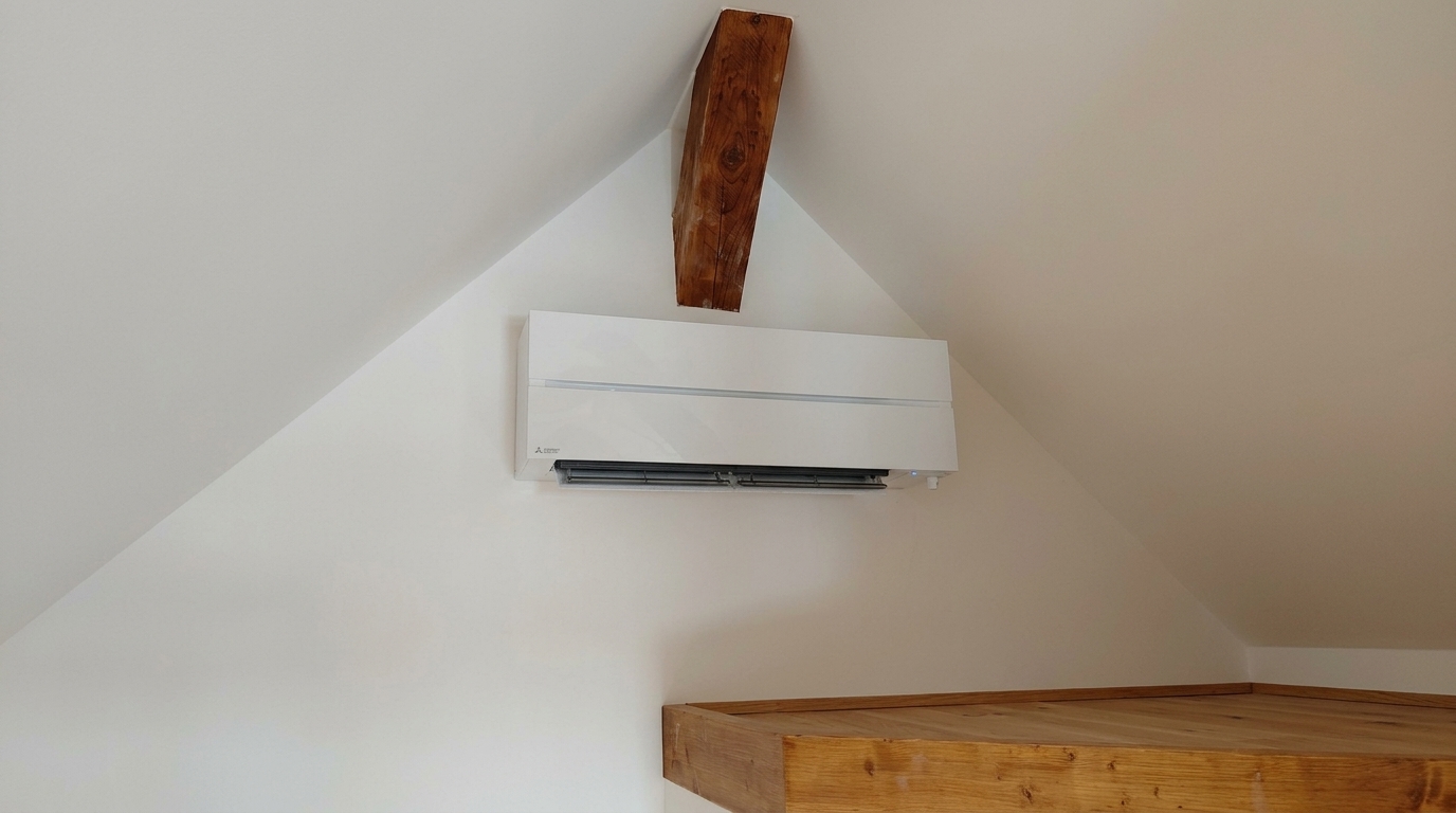 Weisses Mitsubishi-Innengerät unter der Dachschräge neben einem freigelegten Holzbalken