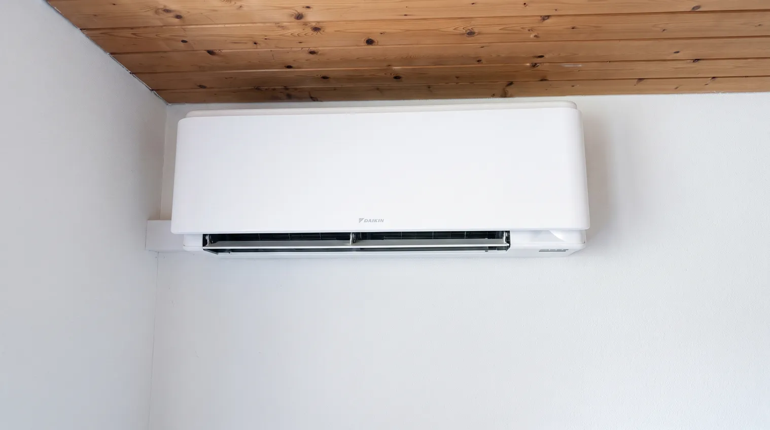 Weisses Daikin-Innengerät an heller Wand unter einer Holzdecke