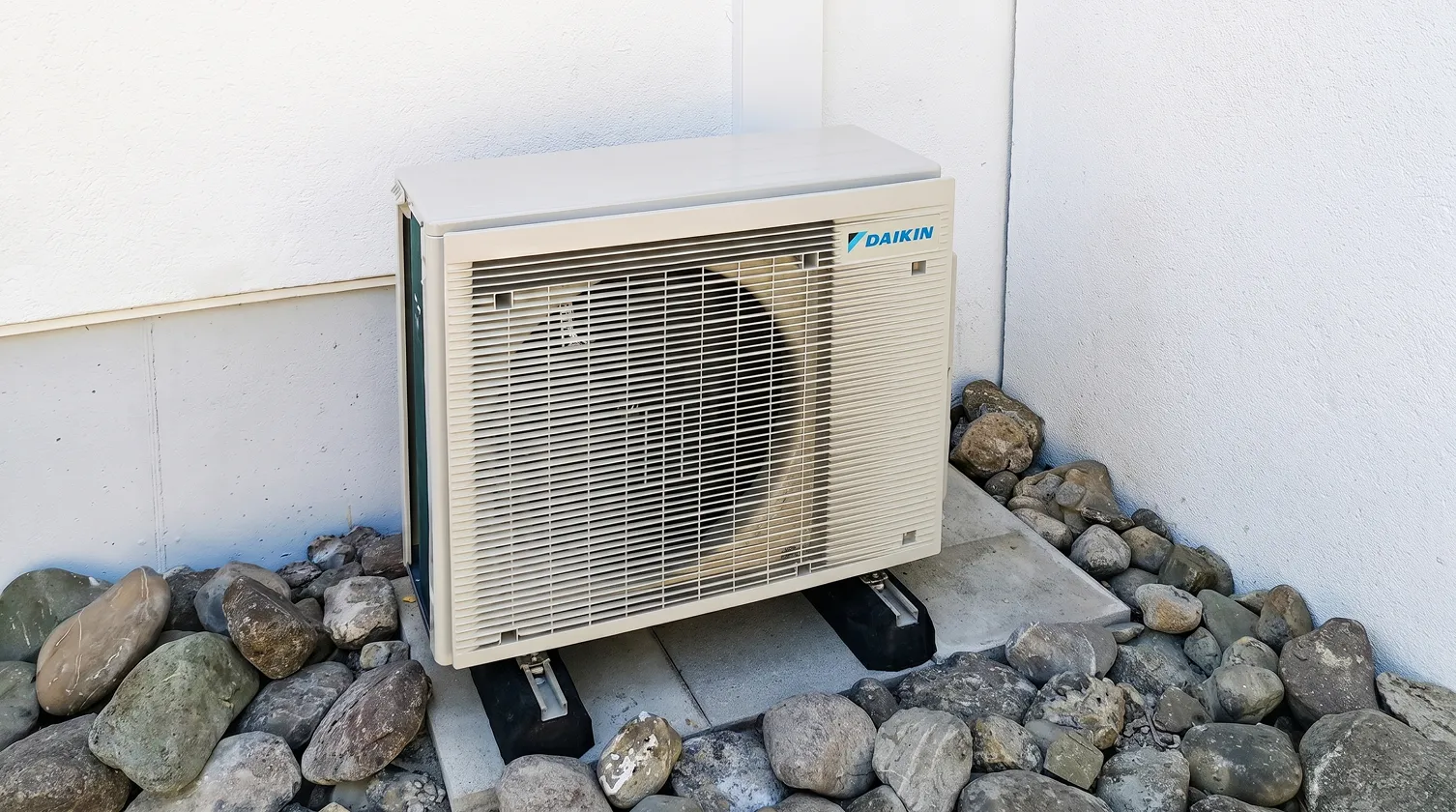 Daikin-Aussengerät auf Betonplatten im Kiesbett an der Hausecke