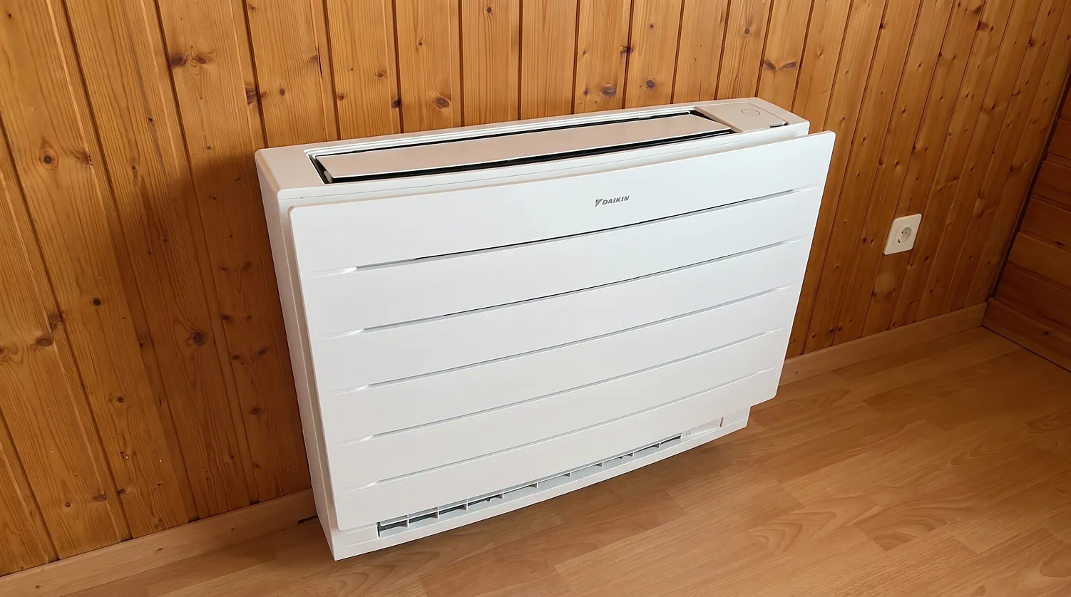 Weisses Daikin-Truhengerät vor einer Holzwand auf Parkettboden