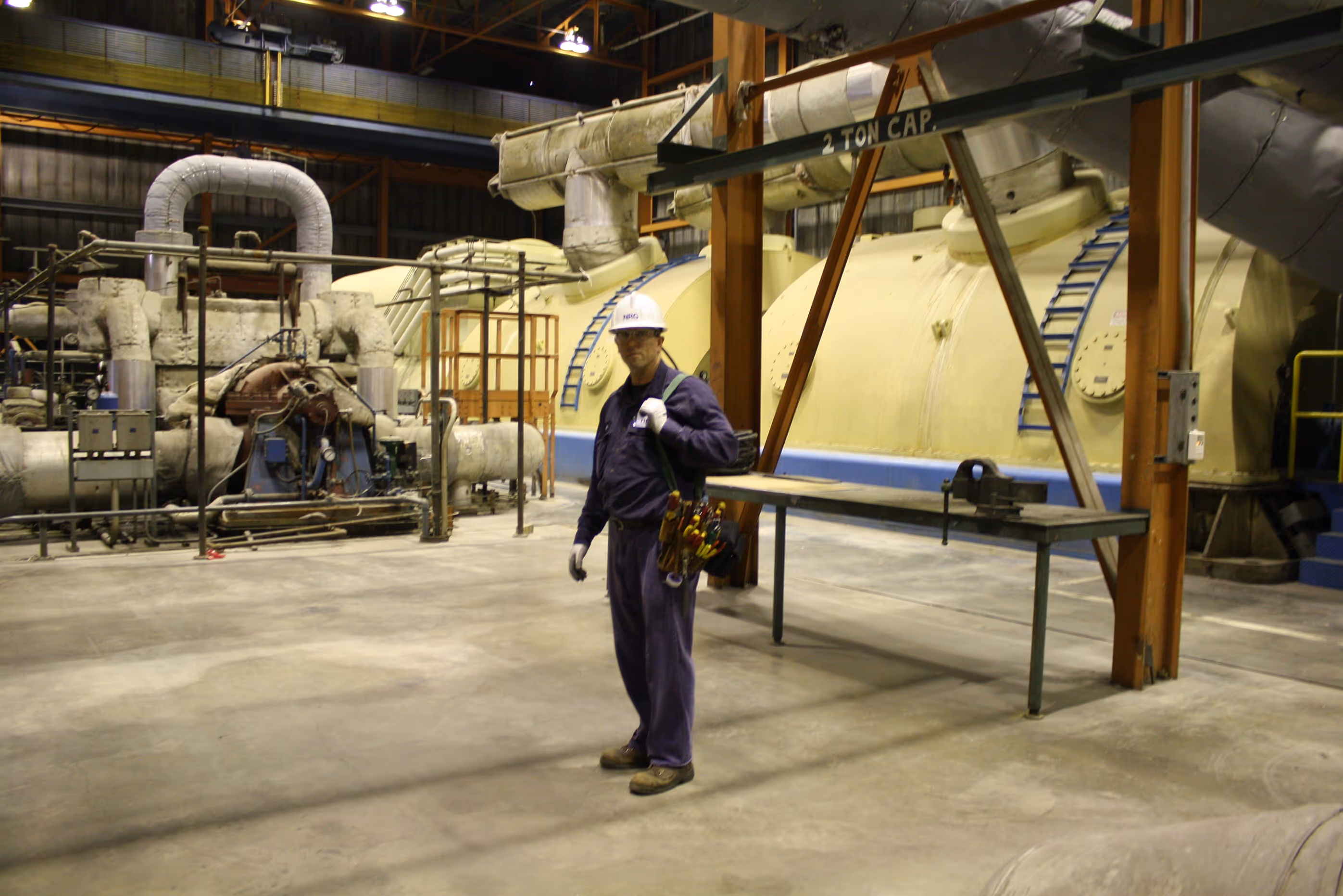 Electrical worker in front of large pipes.