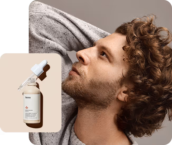 Side profile of a young man with curly hair wearing a gray sweater, alongside a dropper bottle of skincare serum labeled 'heros'.