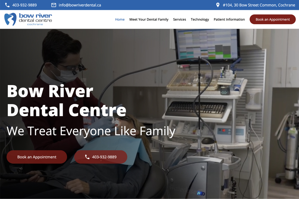 Dentist wearing magnifying glasses and mask treating patient reclining in dental chair in a modern clinic.