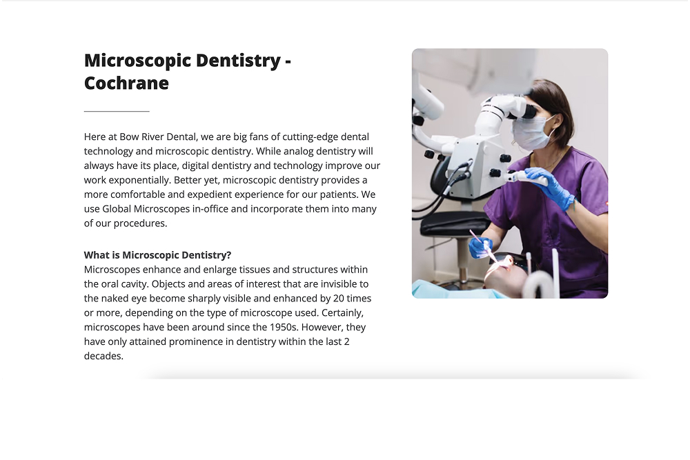Dentist in purple scrubs and mask using a dental microscope while treating a patient.