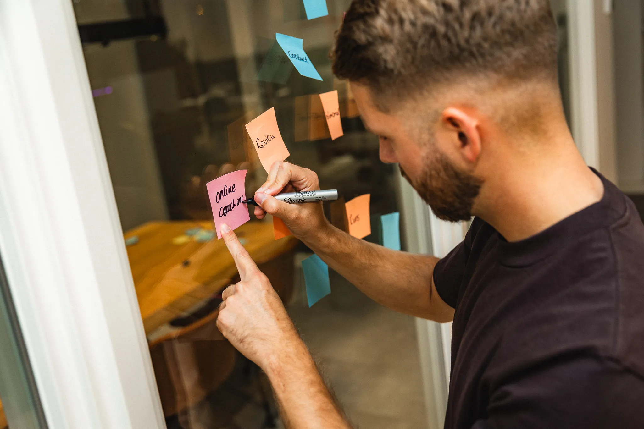Designer schrijft ideeën op post-its tijdens een brainstormsessie met klant