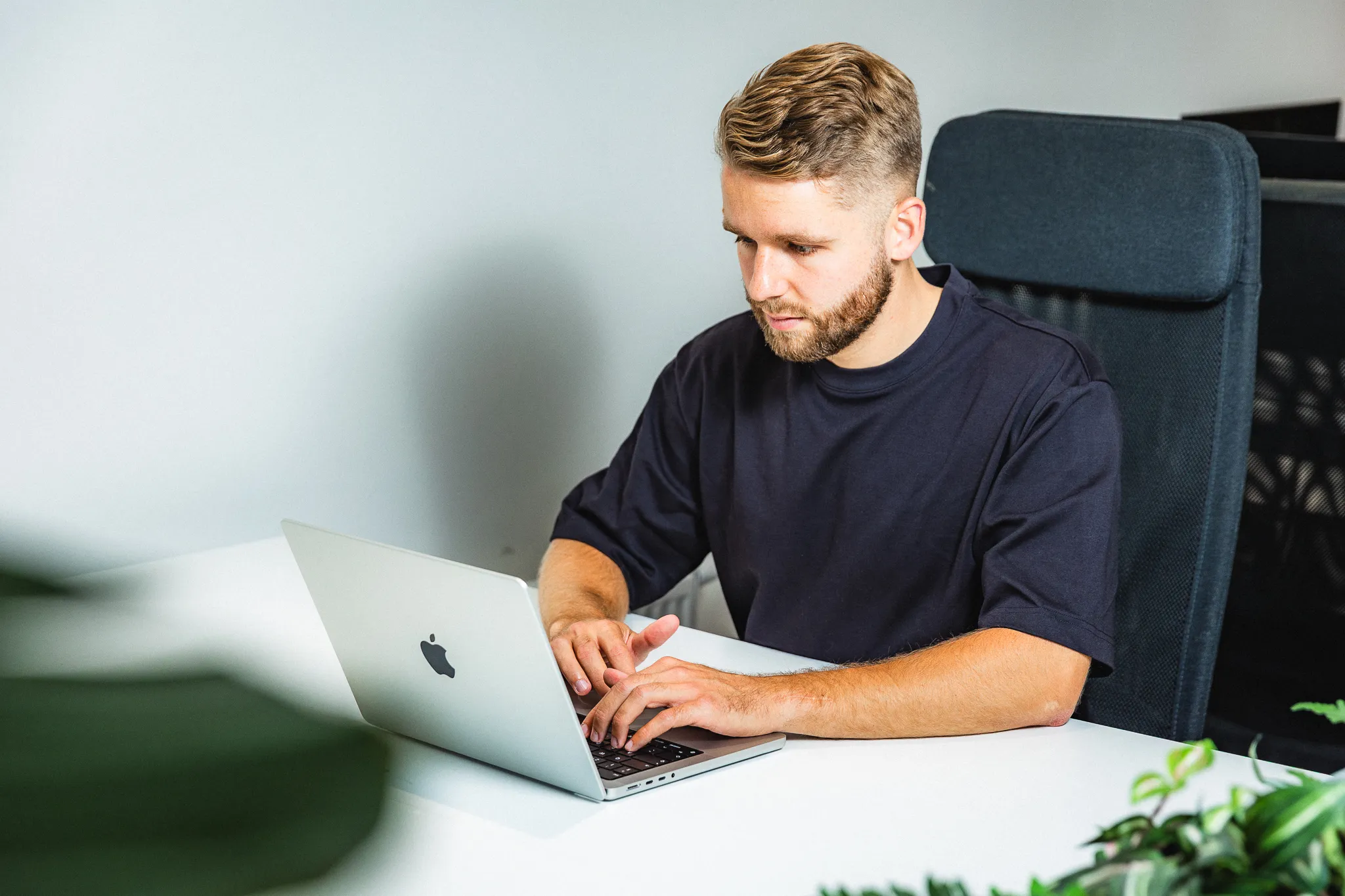 Designer aan het werk op laptop met groene planten op achtergrond in creatieve werkomgeving