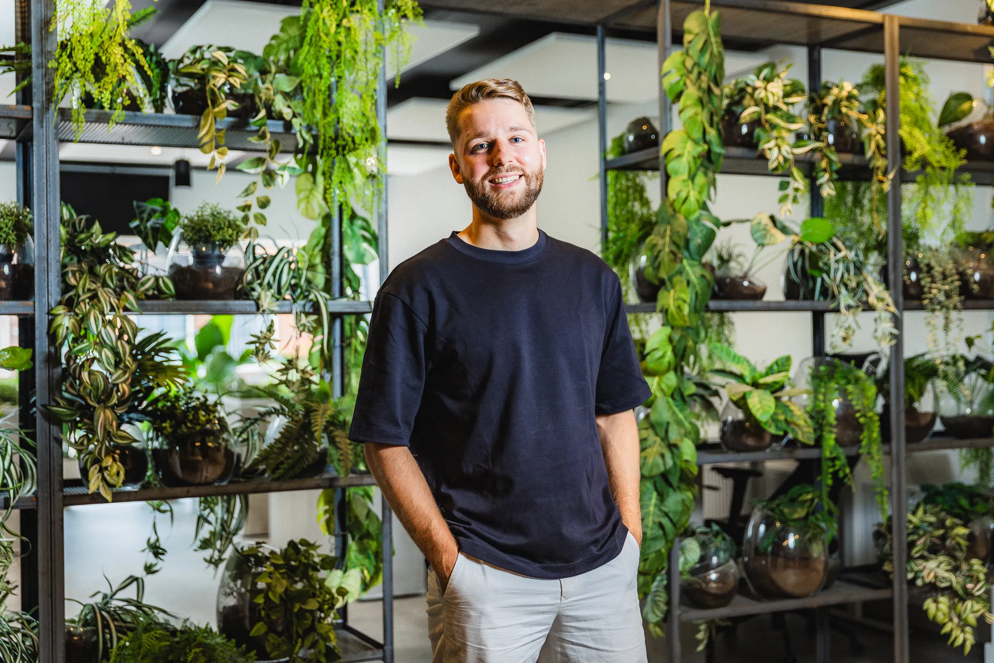Portret van Diedrik tussen planten in lichte werkruimte