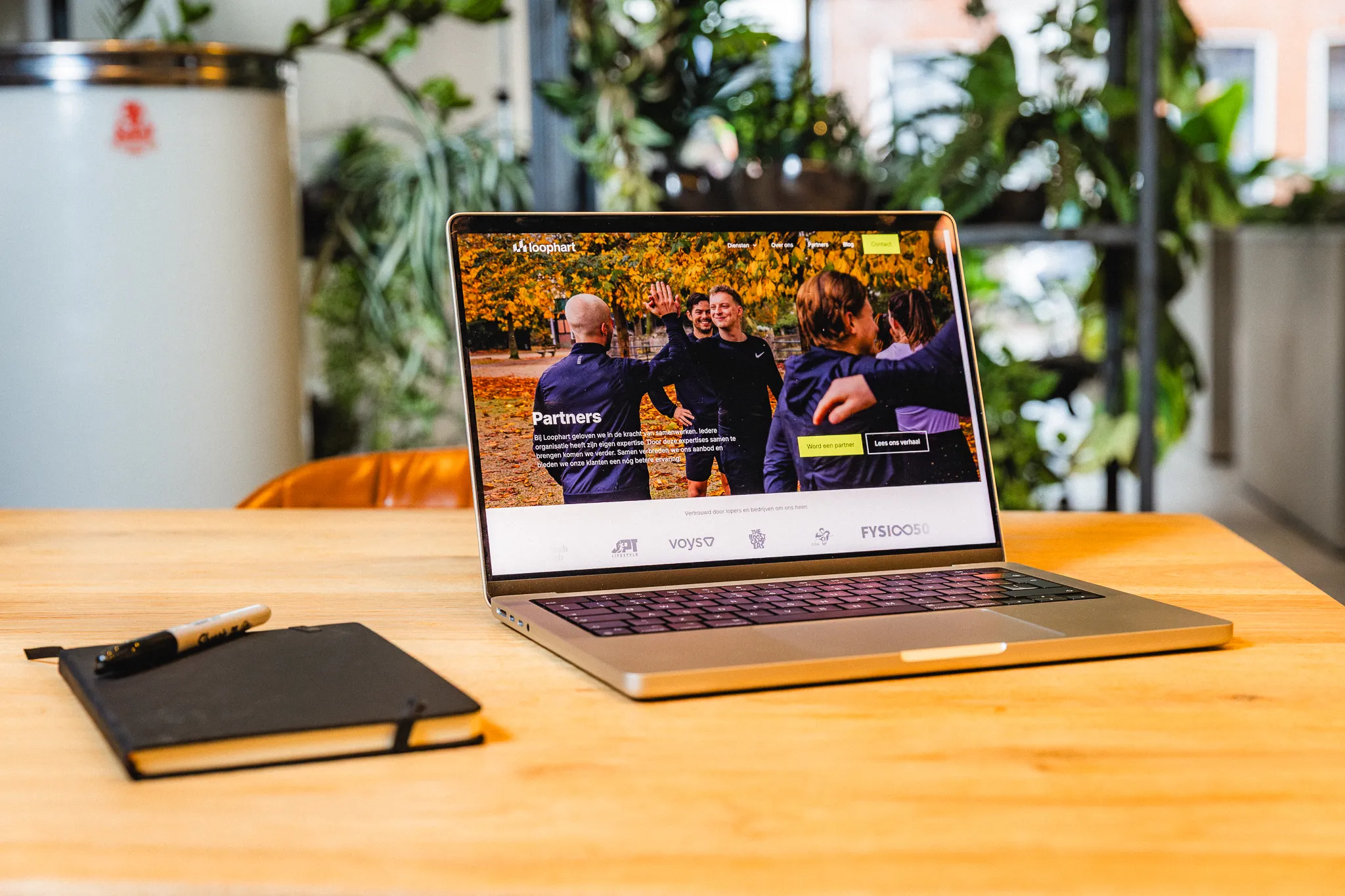 Sfeerfoto van laptop met website van Loophart en zwart notitieboekje op tafel