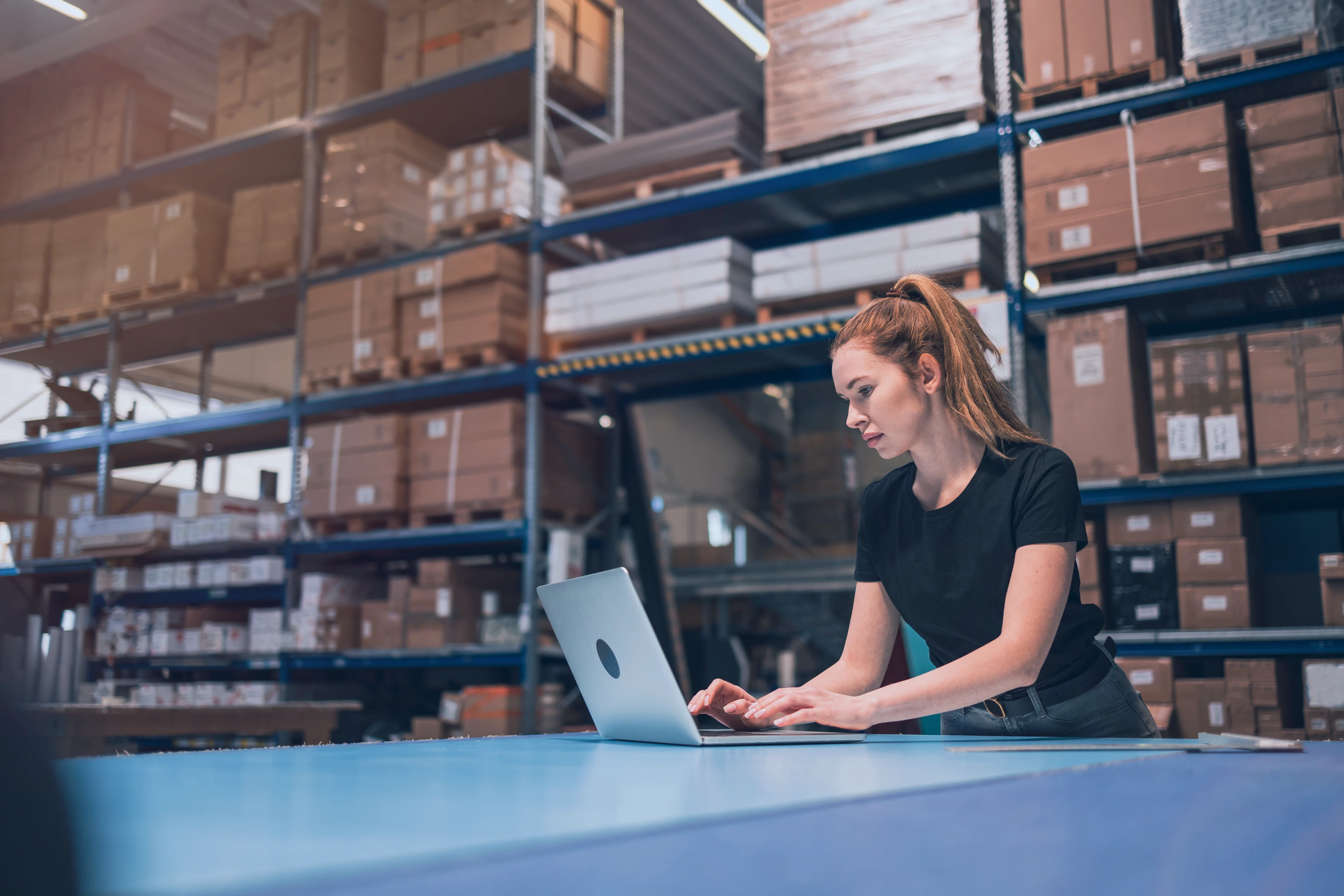 Woman working on a laptop in shipping warehouse