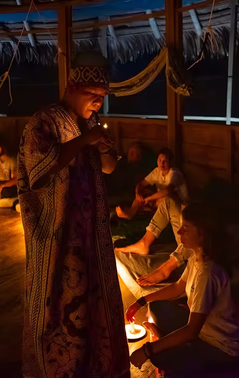  sacred nighttime ritual unfolds as a shaman lights a candle, guiding participants through a ceremonial moment of reflection and connection.