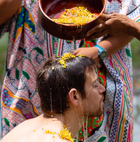 Water and flower petals poured over man's head during a cleansing ritual.