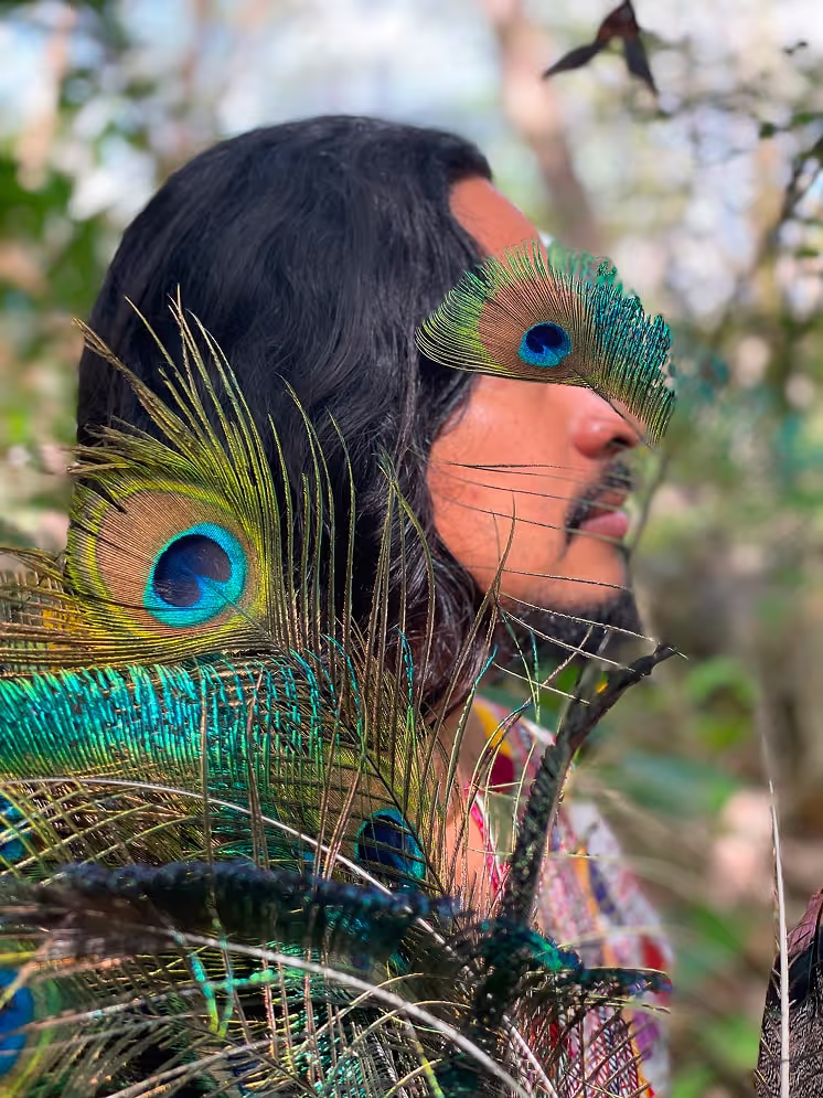 Close-up of a shaman holding vibrant peacock feathers during a ceremonial moment in the forest, symbolizing vision and spiritual insight.
