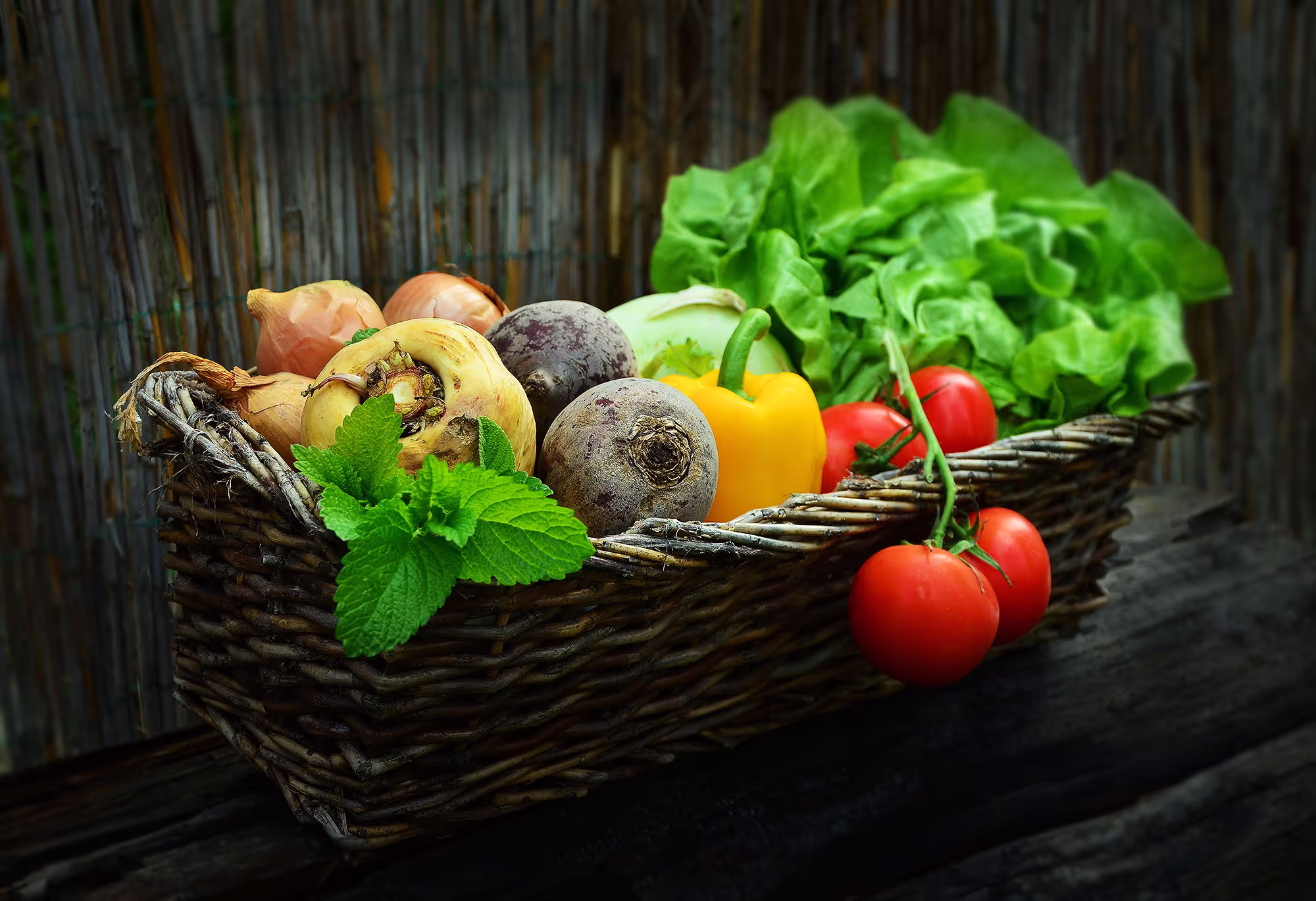 Woven basket filled with fresh vegetables and herbs including tomatoes, lettuce, beets, onions, and mint—ideal for ayahuasca dieta meal preparation.