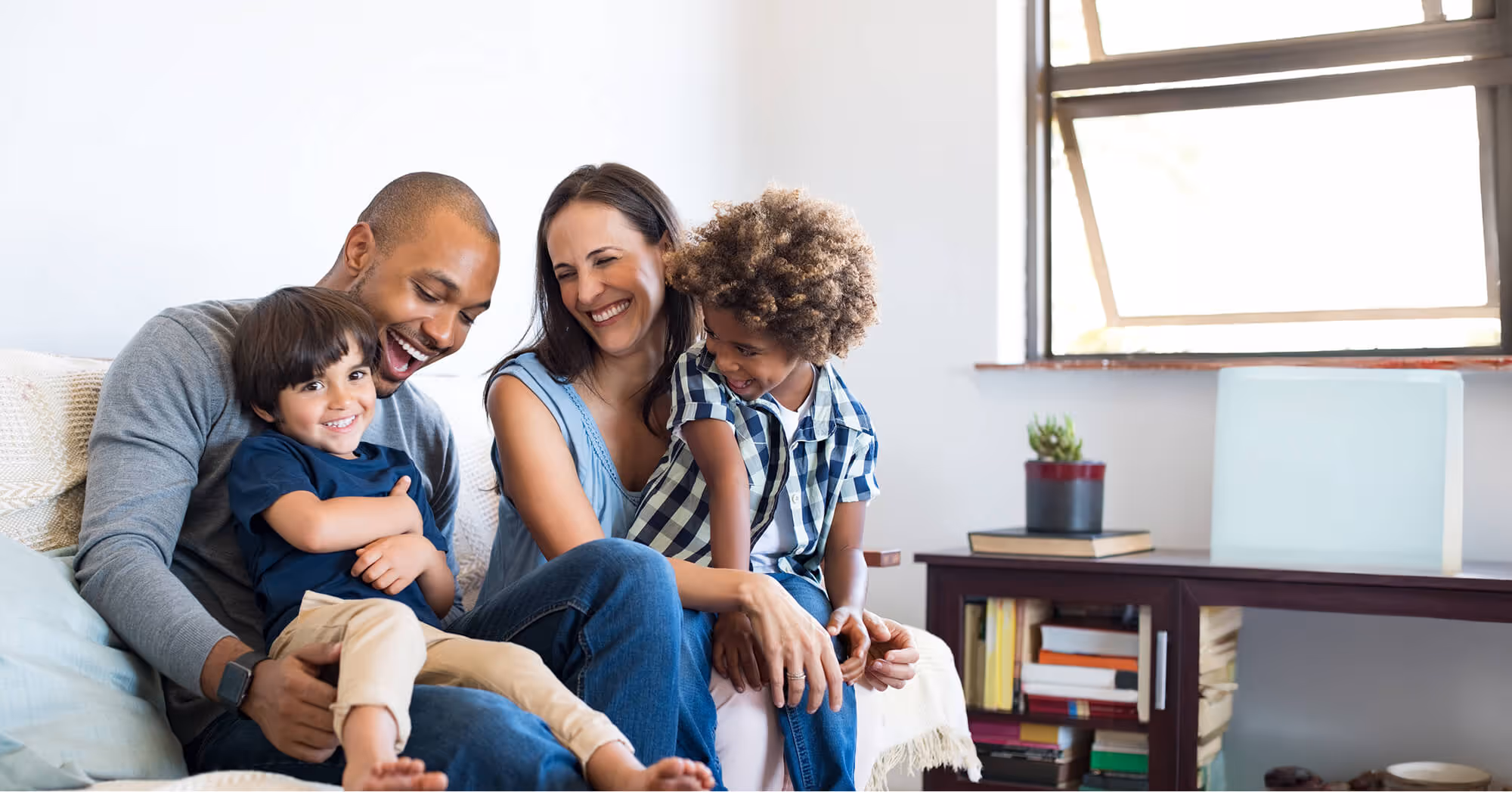 A family sitting on a couch smiling at the camera.