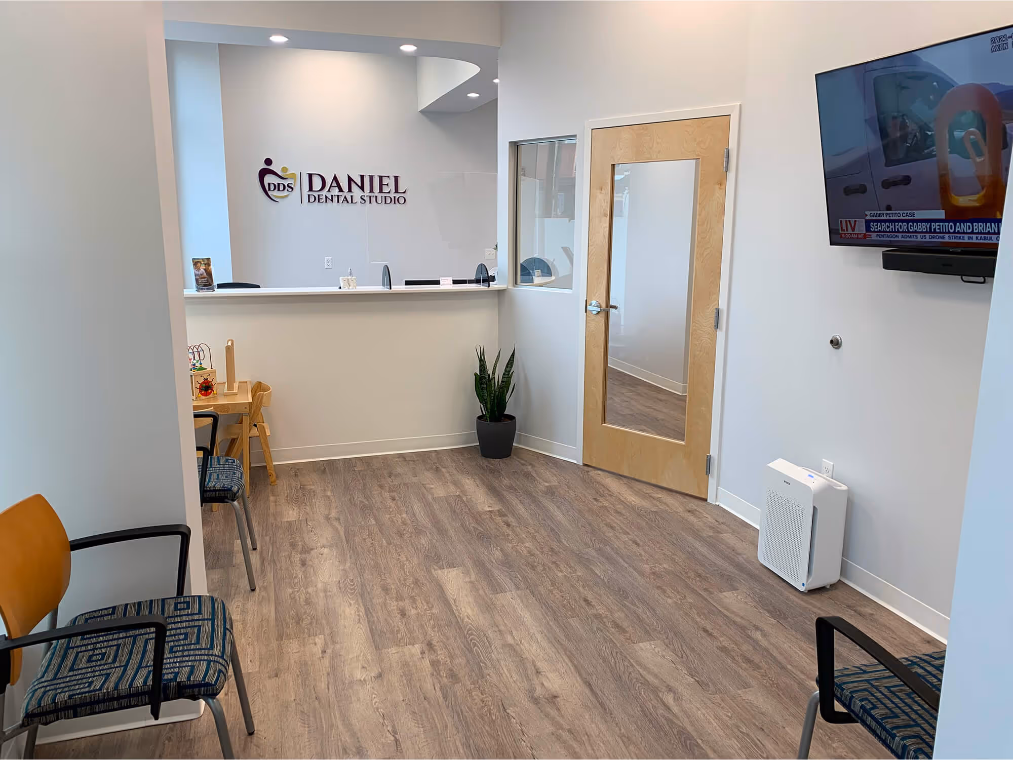 A waiting room with a television and chairs.