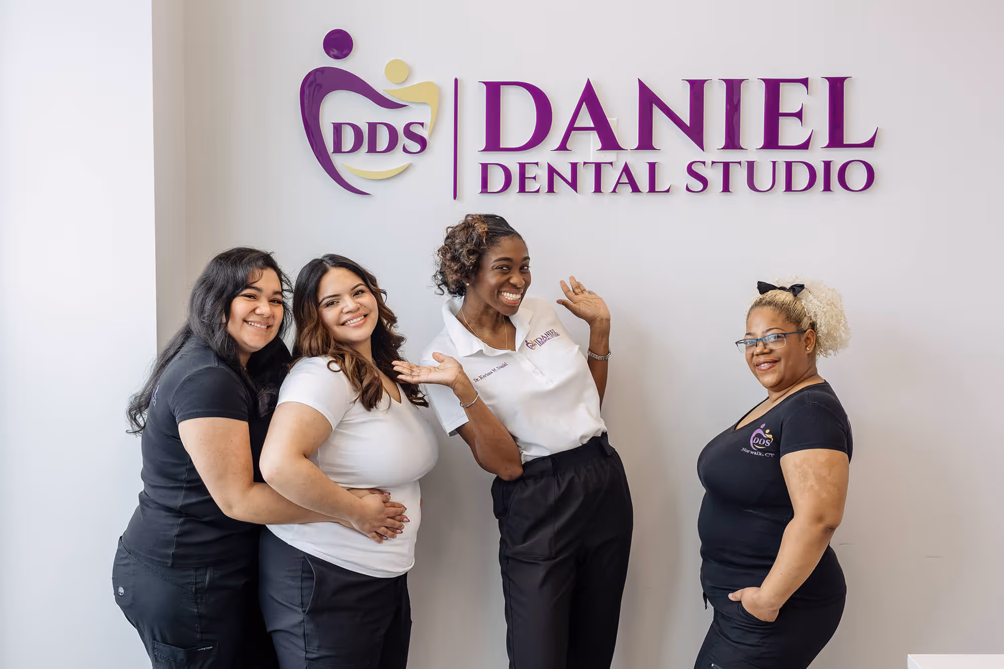 A group of women standing in front of a dental studio sign.