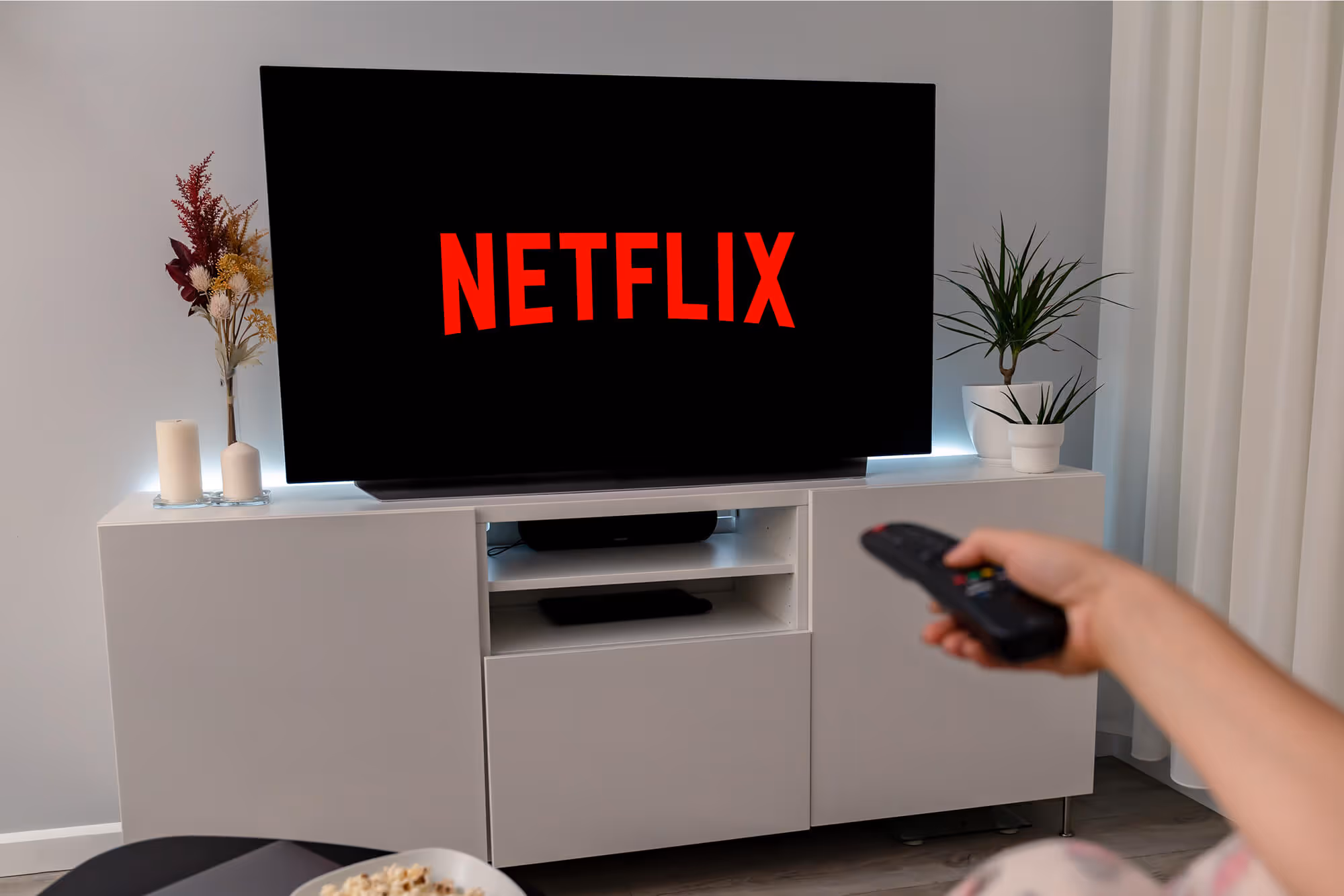 A person holding a remote in front of a television.