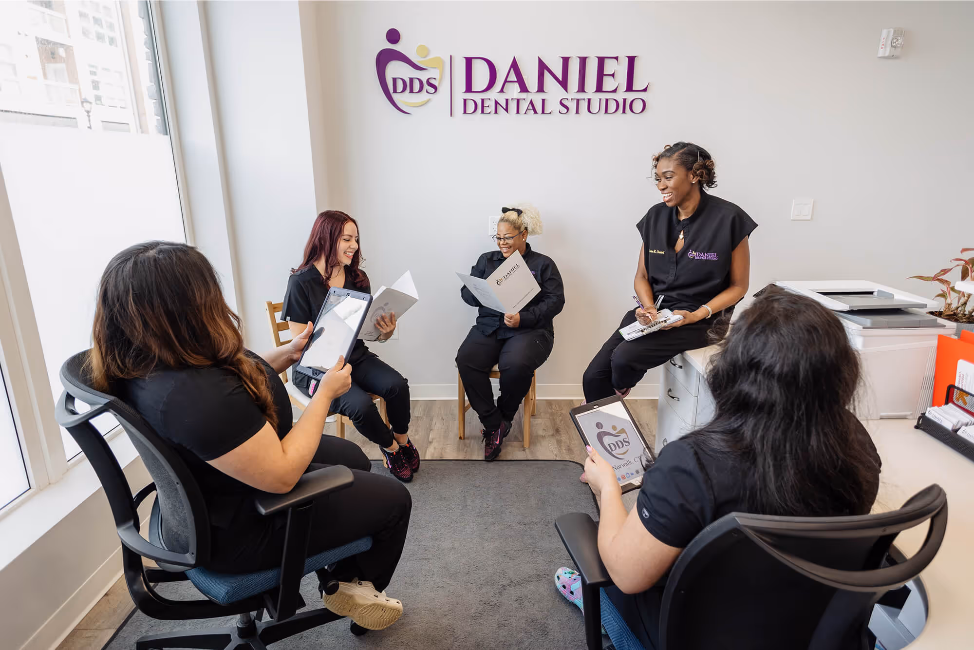A group of women sitting around each other in a room.