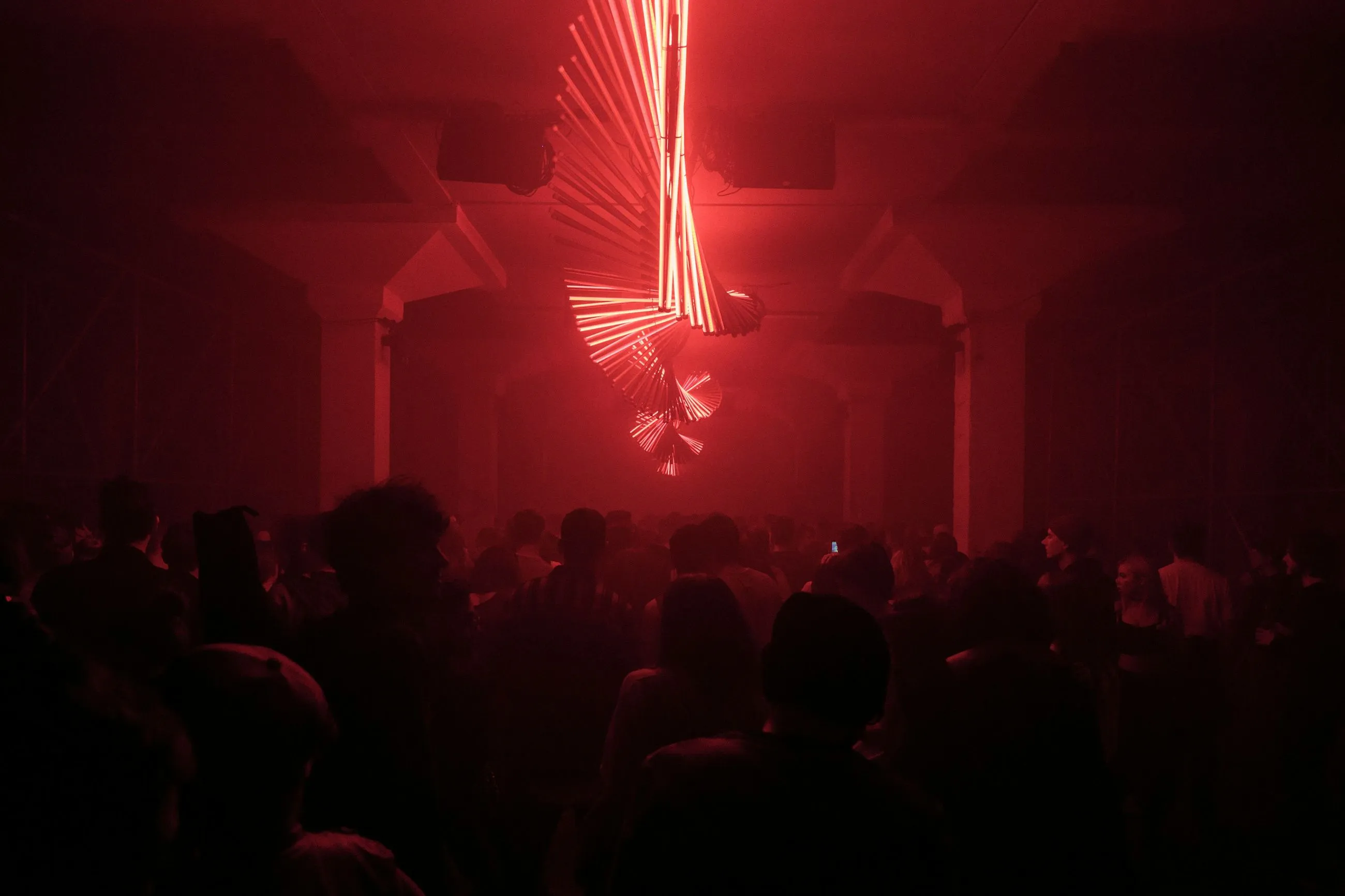 Crowd at dark venue under red spiral lights