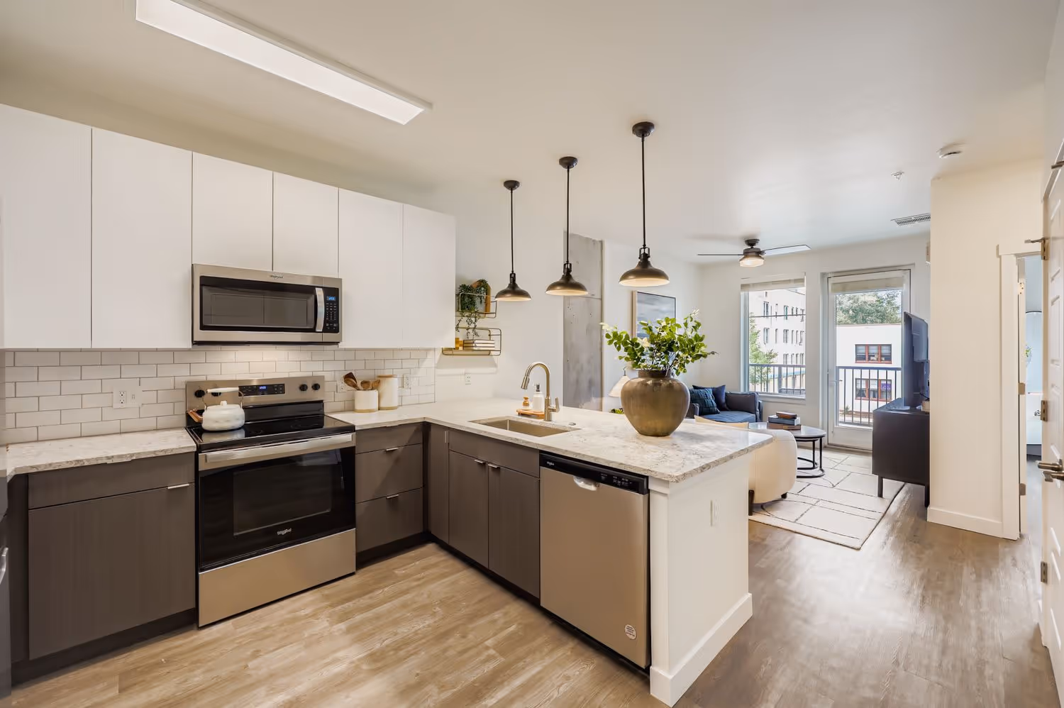 Apartment kitchen with two-tone cabinetry, white subway tile backsplash, and an island that opens to the living area at Avian Apartments in Colorado Springs, CO.