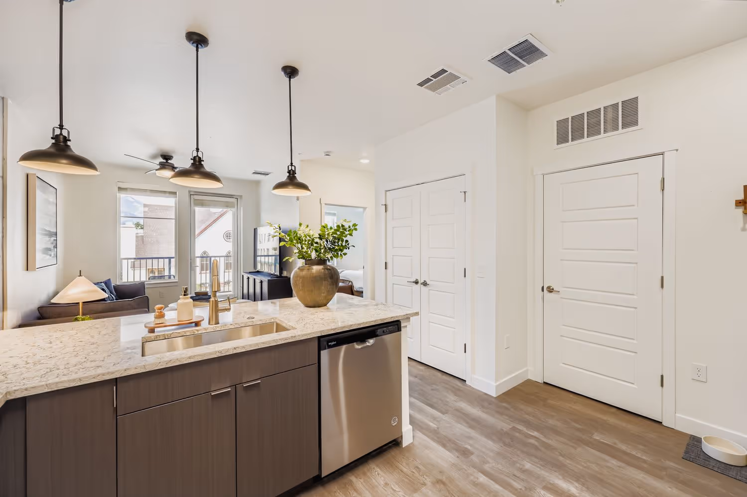 Apartment kitchen island with a sink and dishwasher, offering a view of the open-concept living area at Avian Apartments in Colorado Springs, CO.