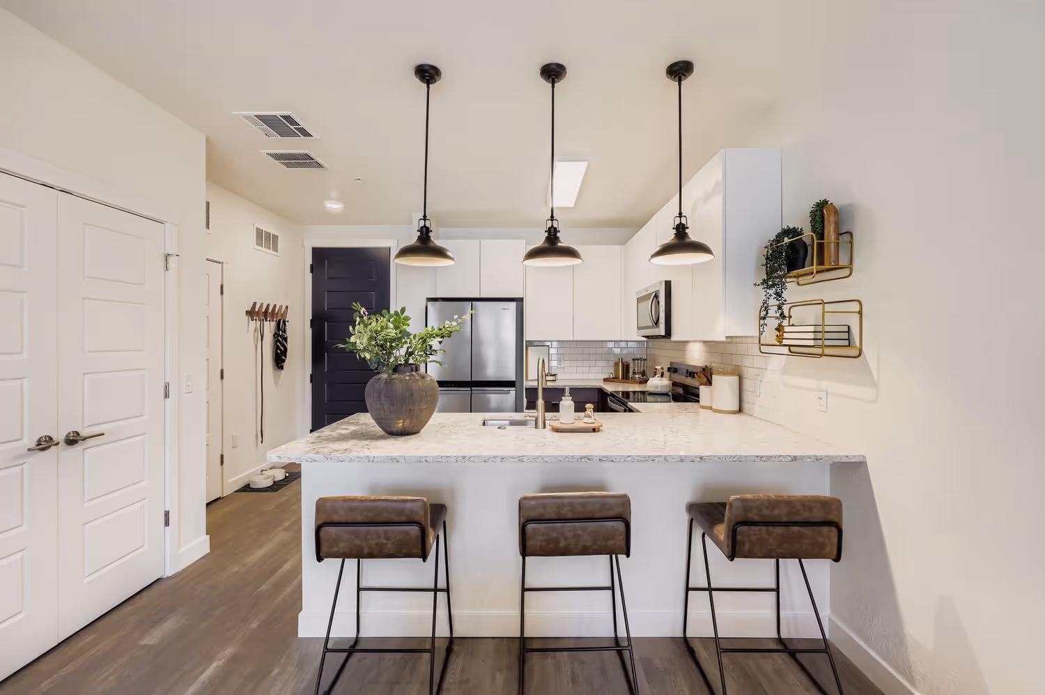 Gourmet apartment kitchen with an island, stone countertops, and modern pendant lighting, showcasing a home at Avian Apartments in Colorado Springs, CO.