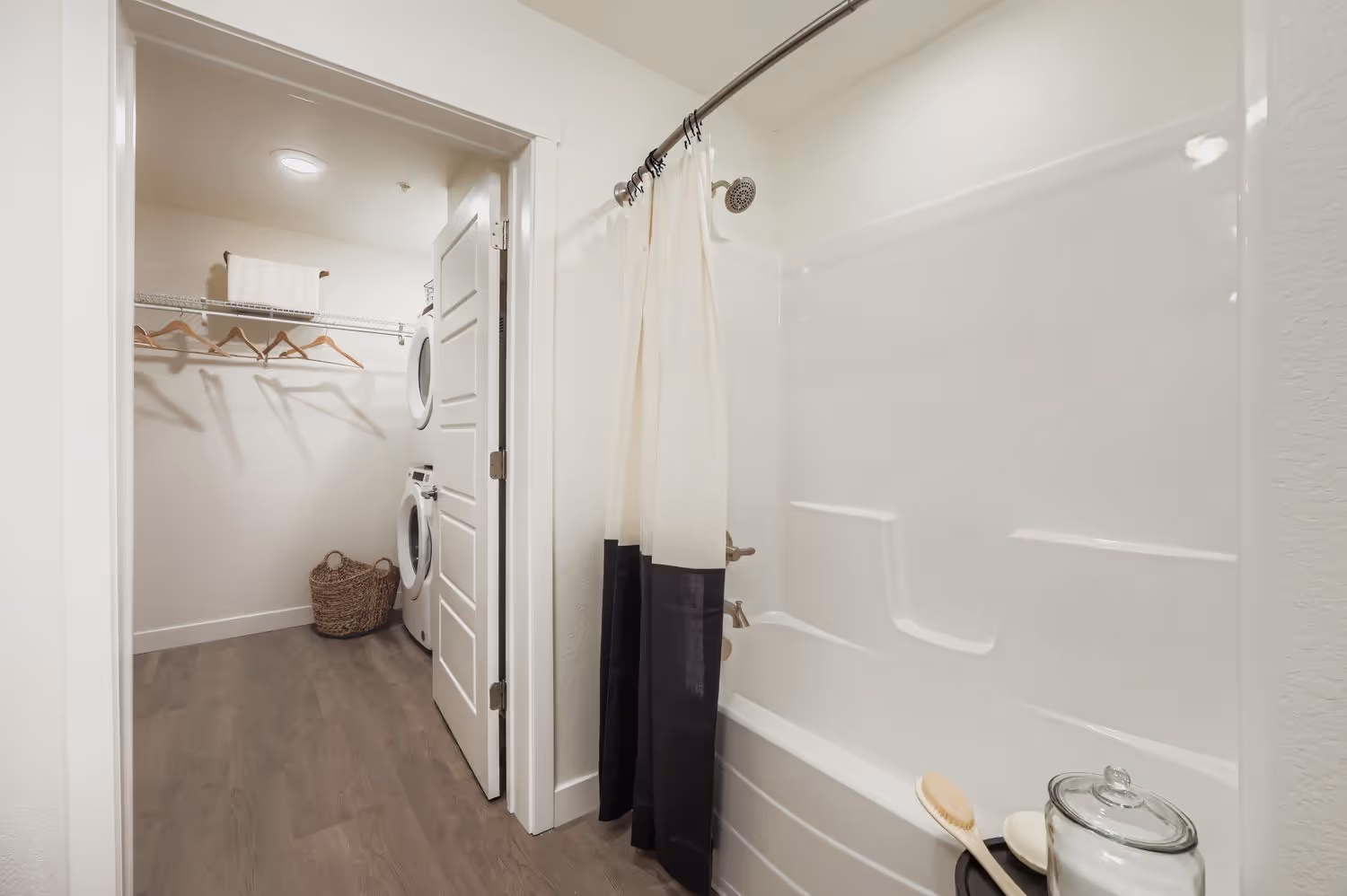 Apartment bathroom with a bathtub and a view into the adjoining walk-in closet and laundry area, showcasing the floor plan at Avian Apartments in Colorado Springs, CO.