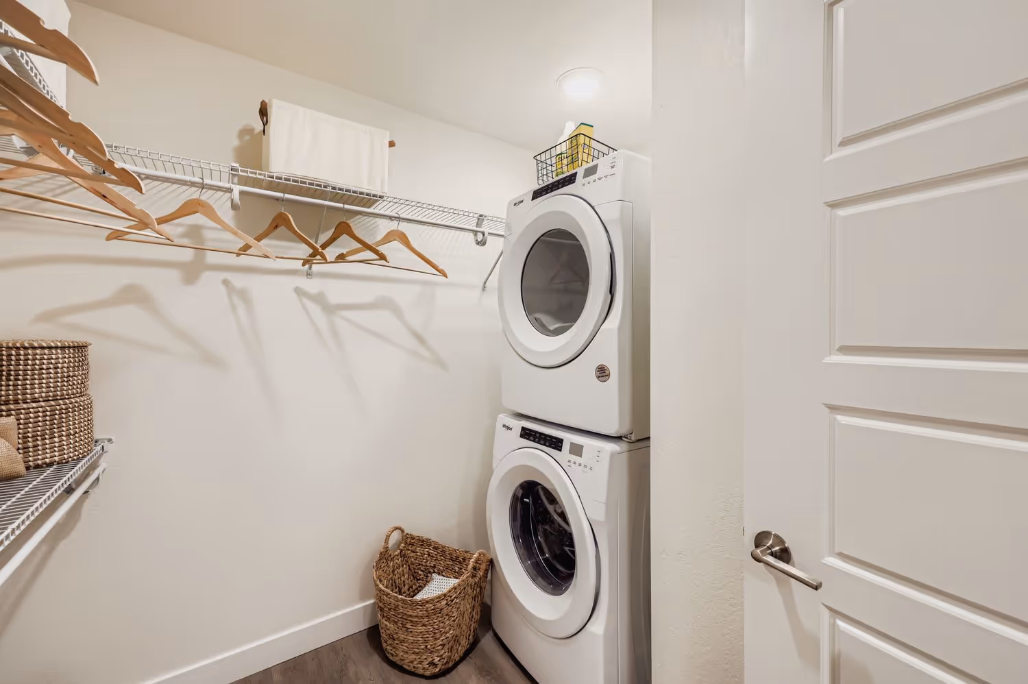 In-unit laundry closet with a stackable washer and dryer and wire shelving for storage, providing resident convenience at Avian Apartments in Colorado Springs, CO.