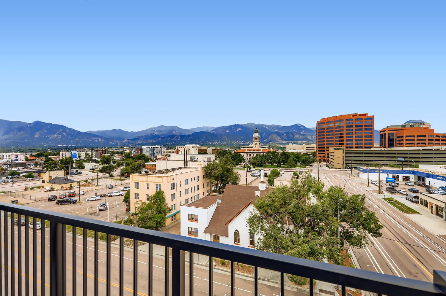 Panoramic view of the downtown Colorado Springs skyline, including buildings and the mountain range, from an apartment balcony at Avian Apartments.