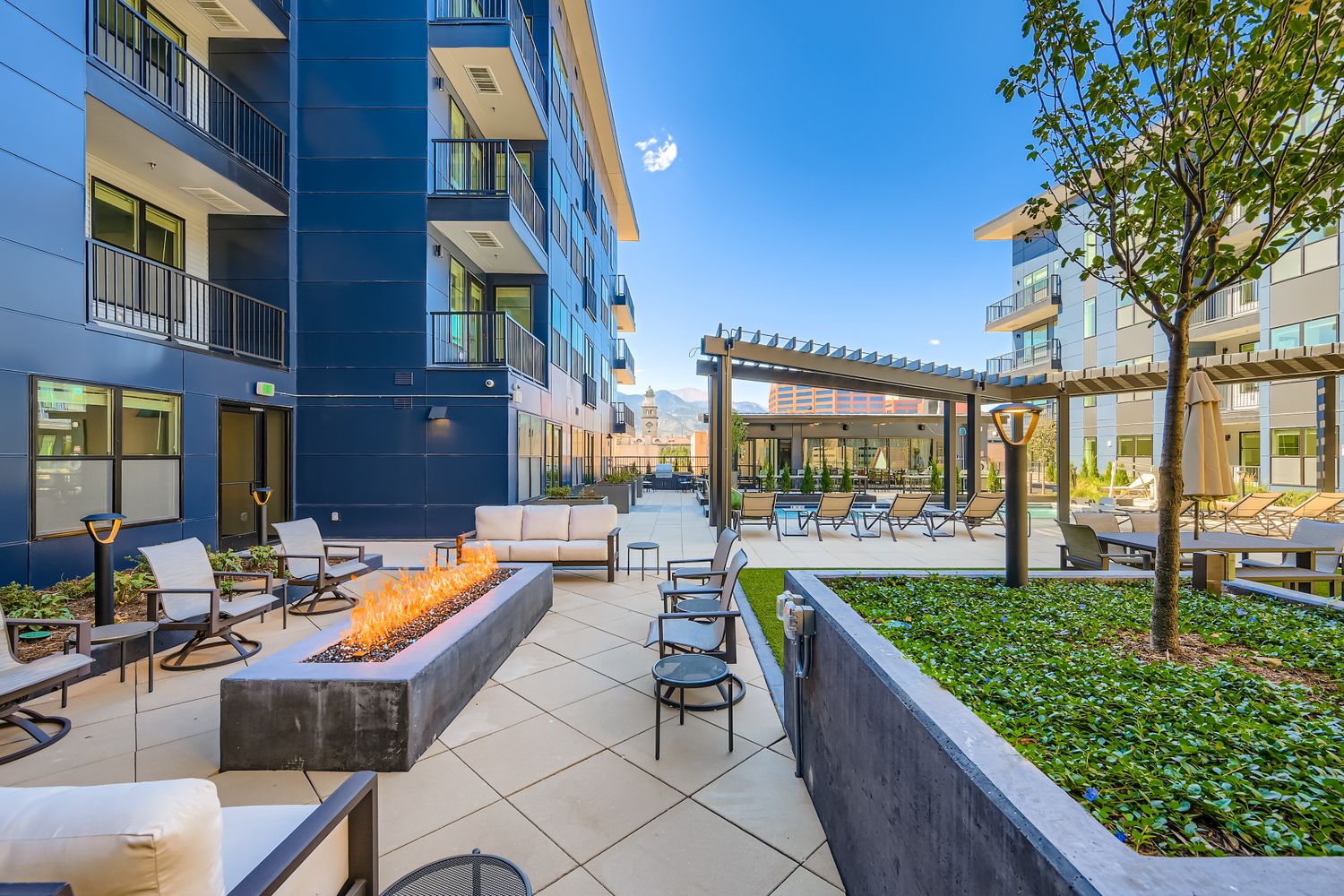 Outdoor resident fire pit lounge area and social space with modern seating, surrounded by the apartment buildings at Avian Apartments in Colorado Springs, CO.