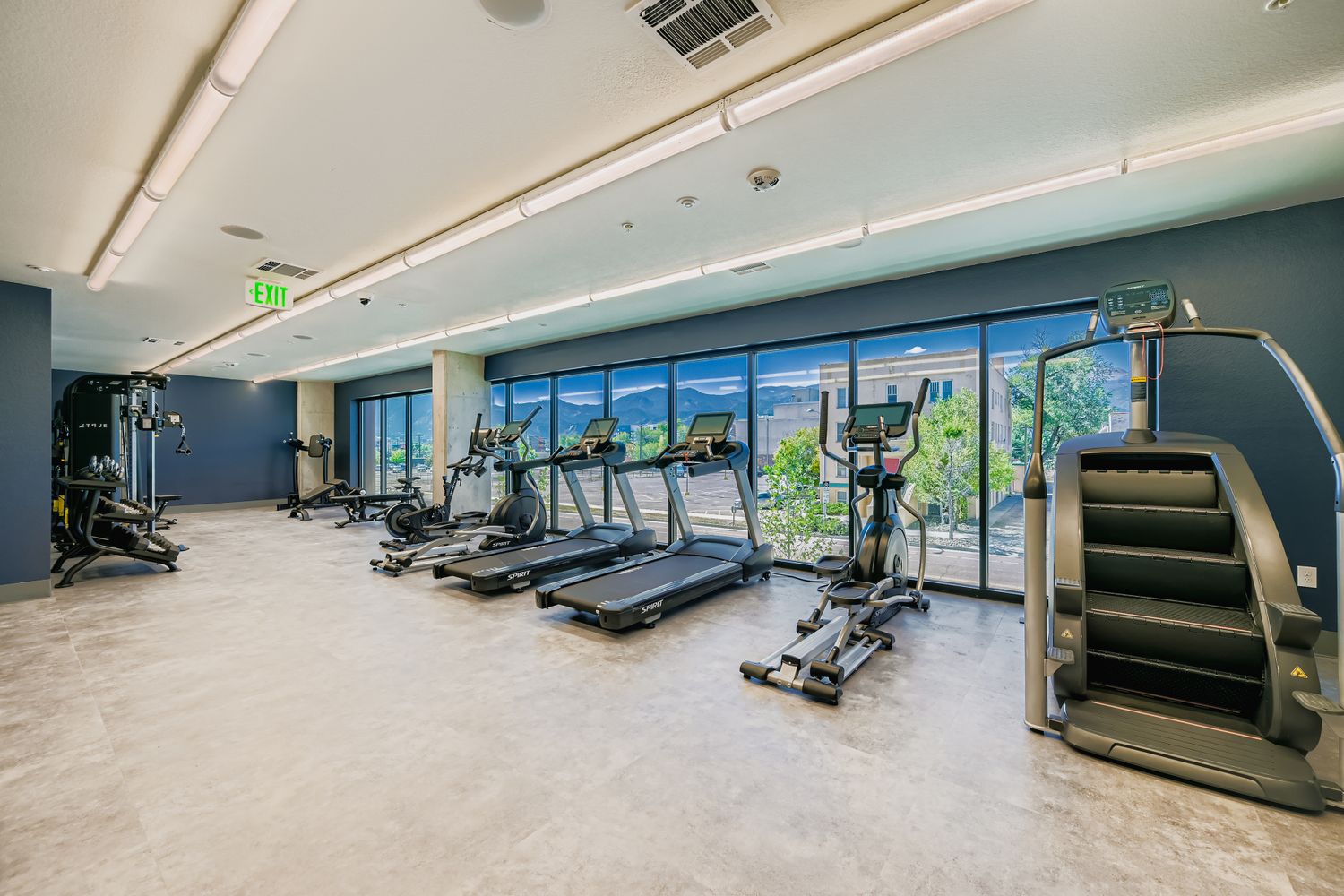 State-of-the-art fitness center with cardio equipment, floor-to-ceiling windows, and mountain views at Avian Apartments in Colorado Springs, CO.