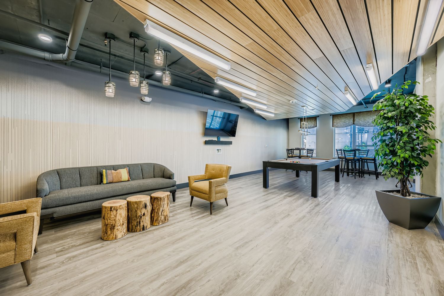 Modern resident lounge and game room with a pool table, comfortable seating, and a large TV at Avian Apartments in Colorado Springs, CO.