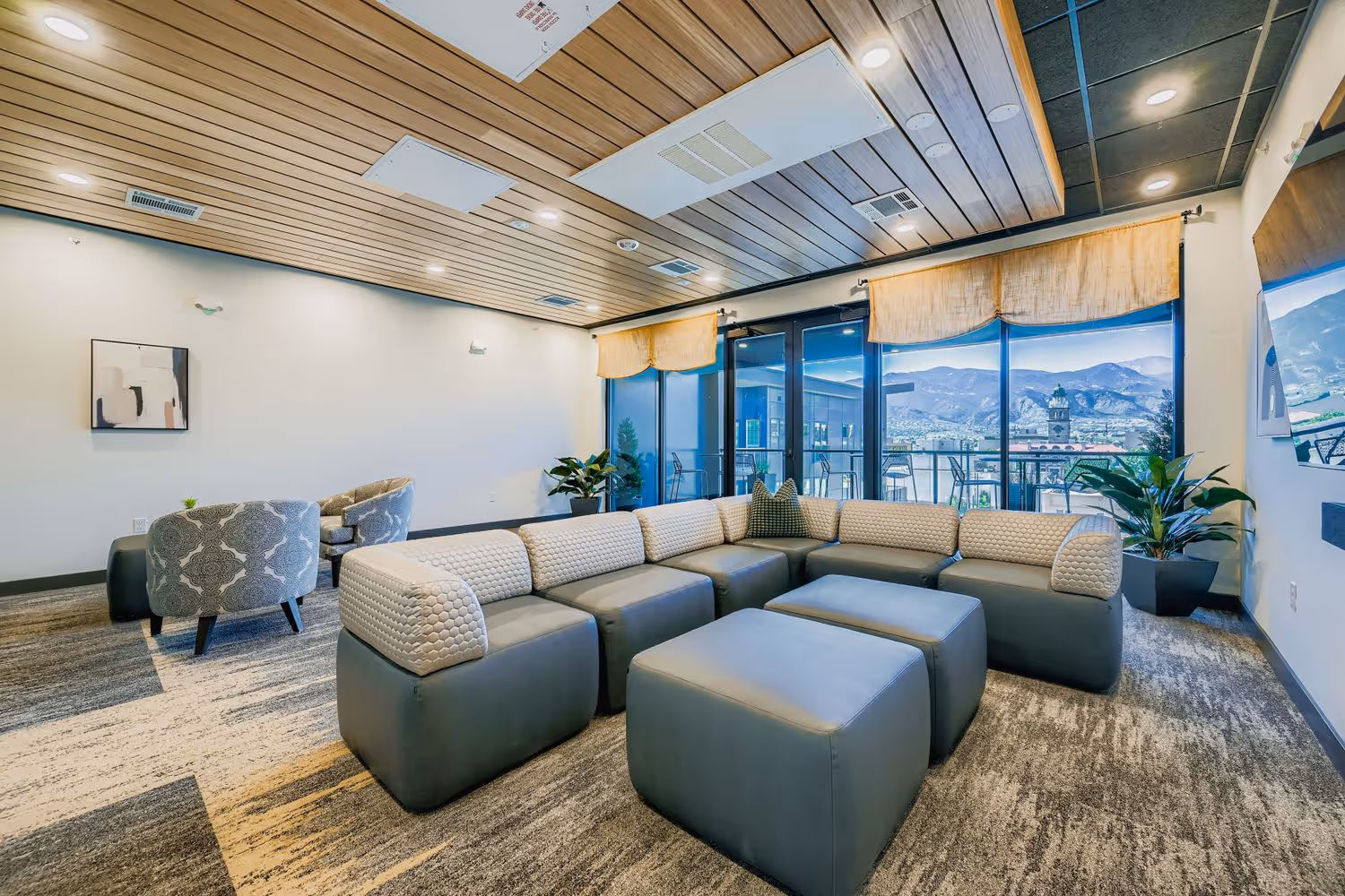 Luxurious resident lounge with comfortable modular seating, a wood slat ceiling, and large windows with mountain views at Avian Apartments in Colorado Springs, CO.