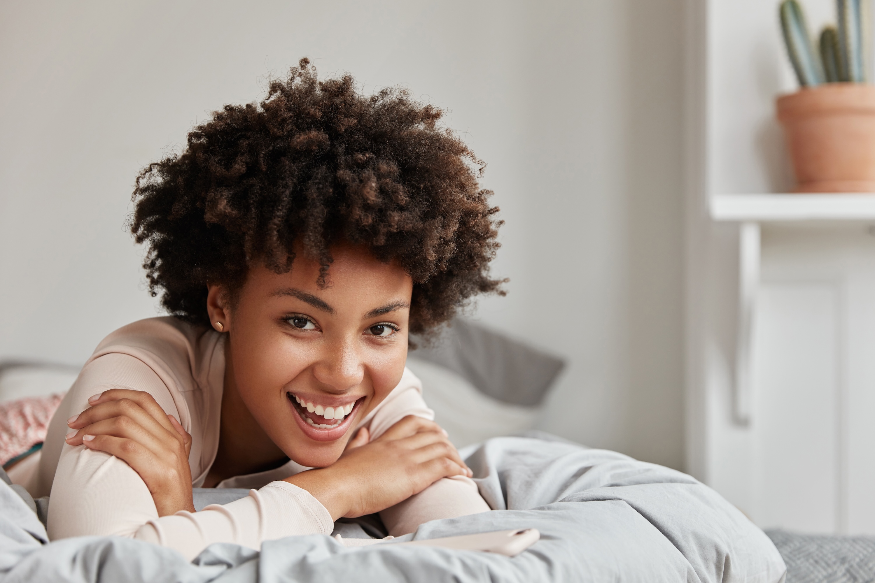 Smiling resident relaxing in a cozy, modern bedroom at Avian Apartments, showcasing comfortable living spaces and bright, stylish apartment interiors.