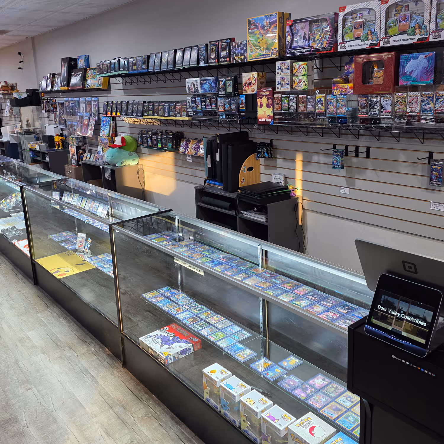 The main display cases and register at Deer Valley Collectibles. Products are arranged in the glass display cases and on shelves behind the counter.