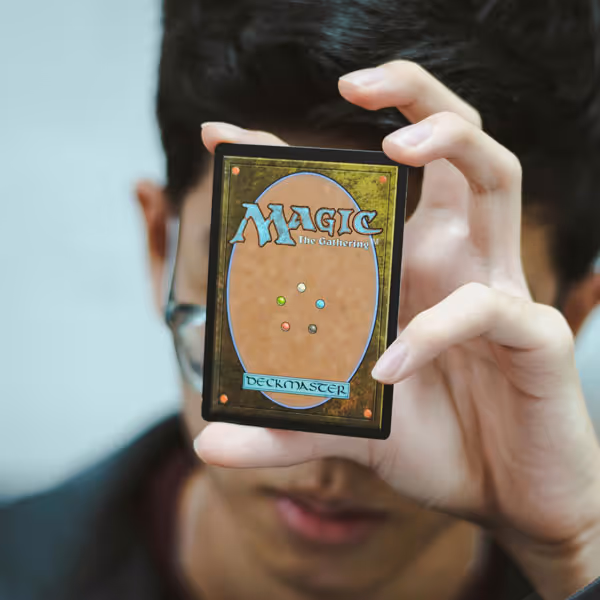 A man holding a Magic: The Gathering card in front of his face as he plays a game.