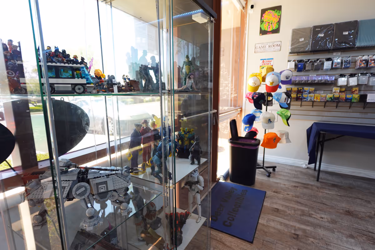 A picture of the inside of a game store, featuring a hat rack and glass display case.