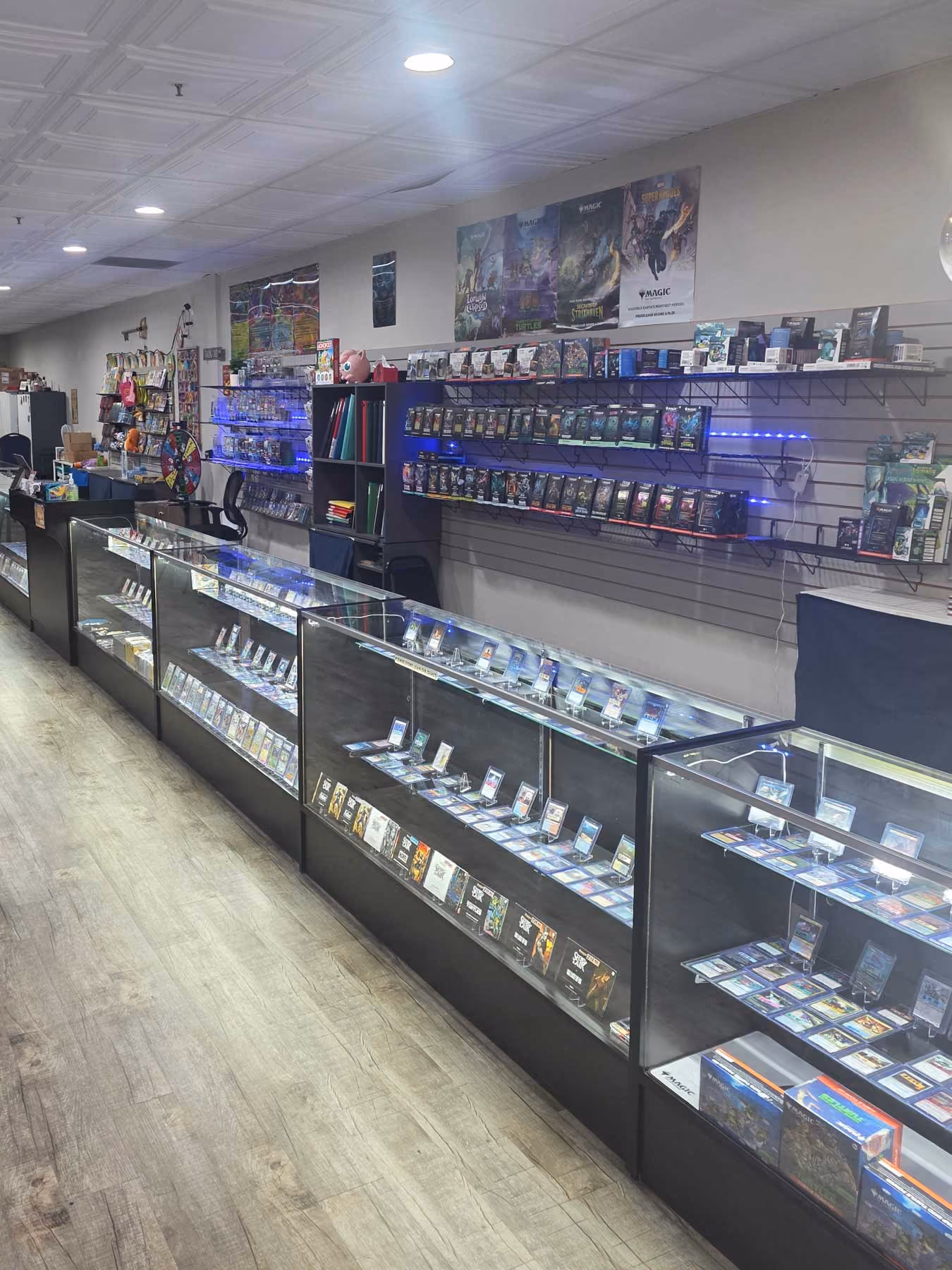 Inside view of a card store with glass display cases filled with trading cards and wall shelves with card packs.
