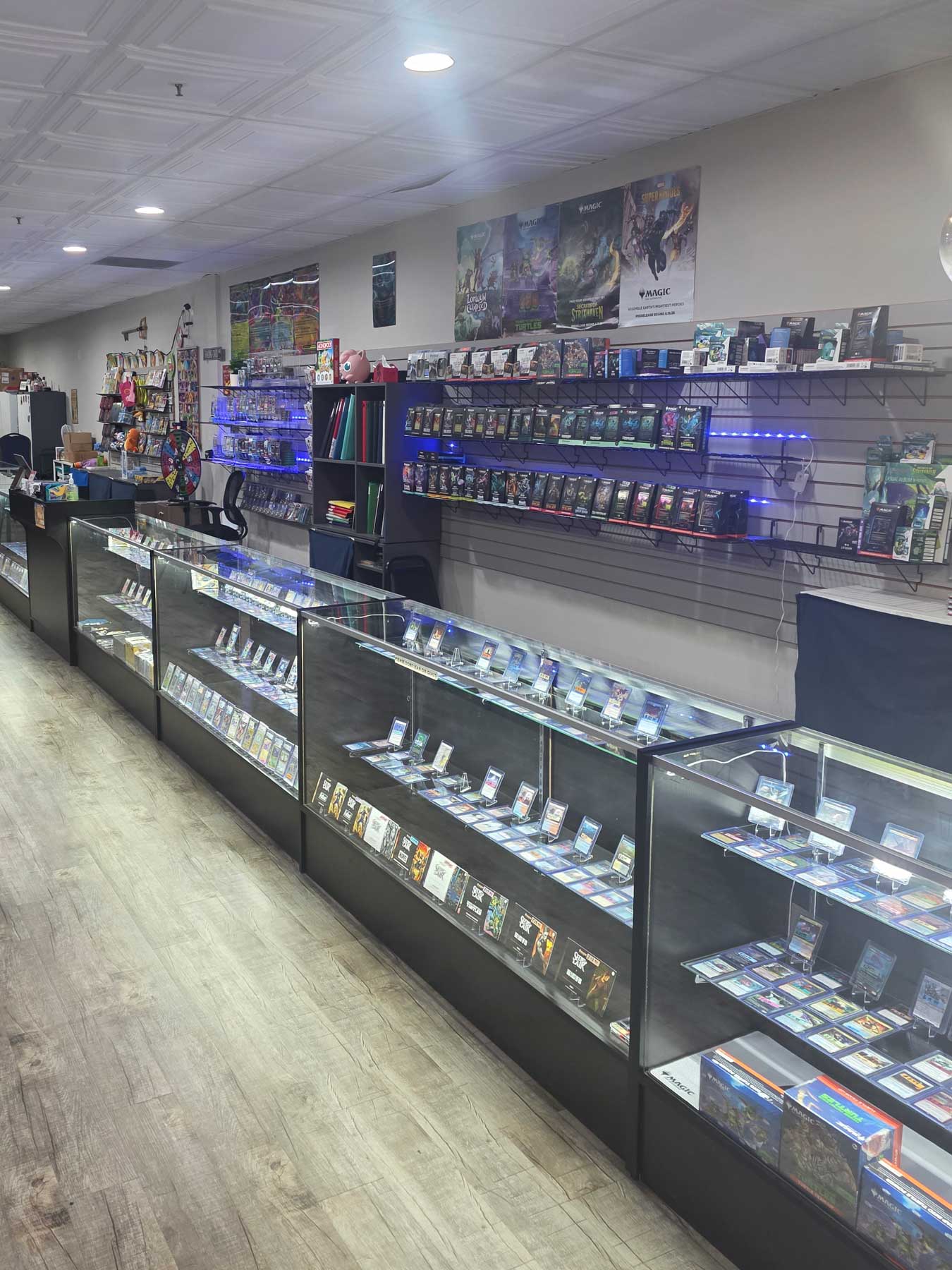 Store interior with glass cases displaying trading cards and shelves stocked with card game merchandise.