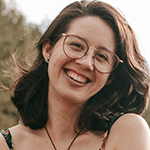 A woman with brunette hair and glasses is looking at the camera