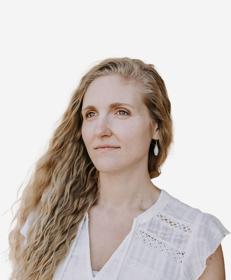 A blonde woman in a white shirt looks ahead thoughtfully.