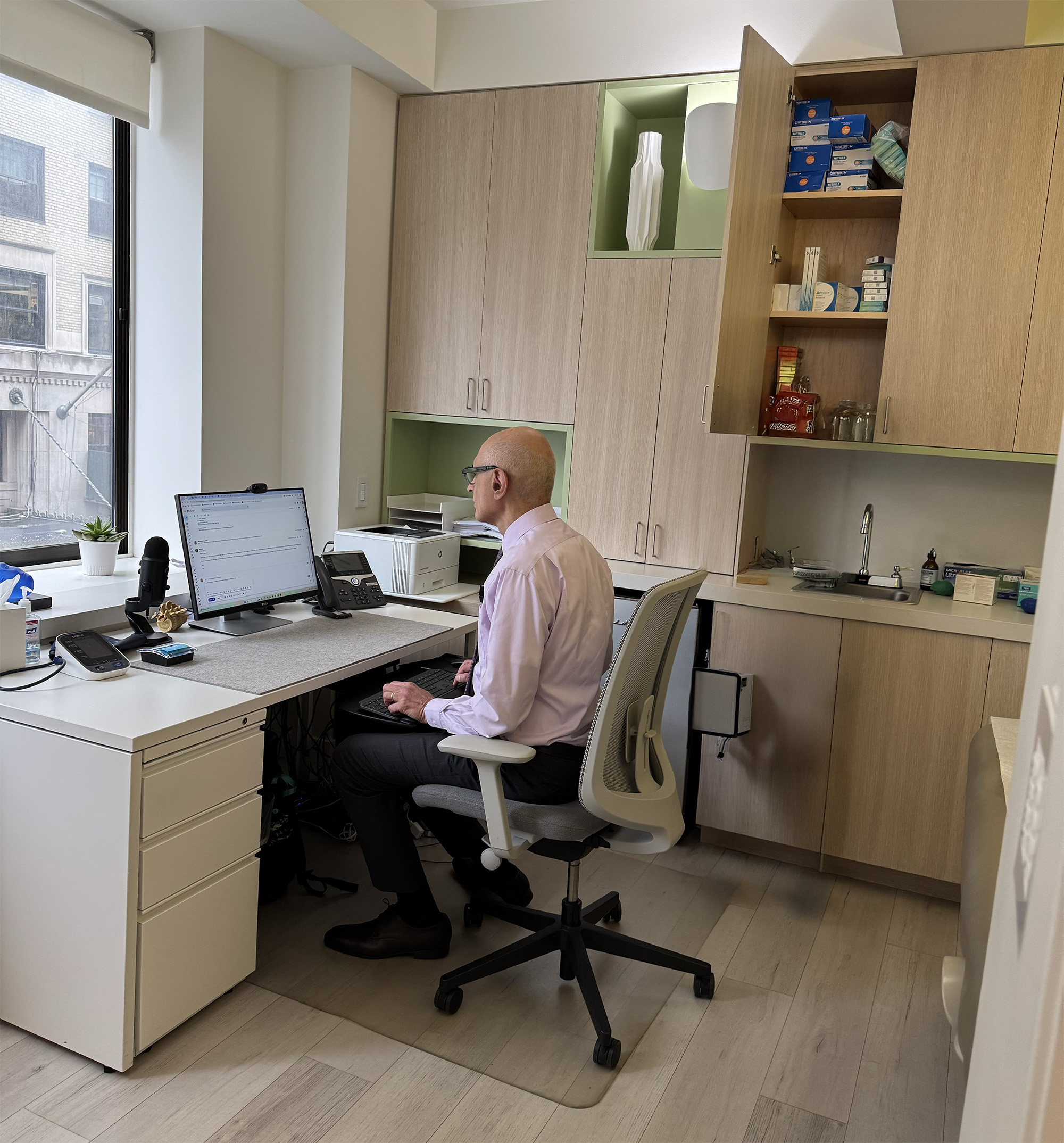 Medical professional analyzing patient data at computer in modern clinical office.