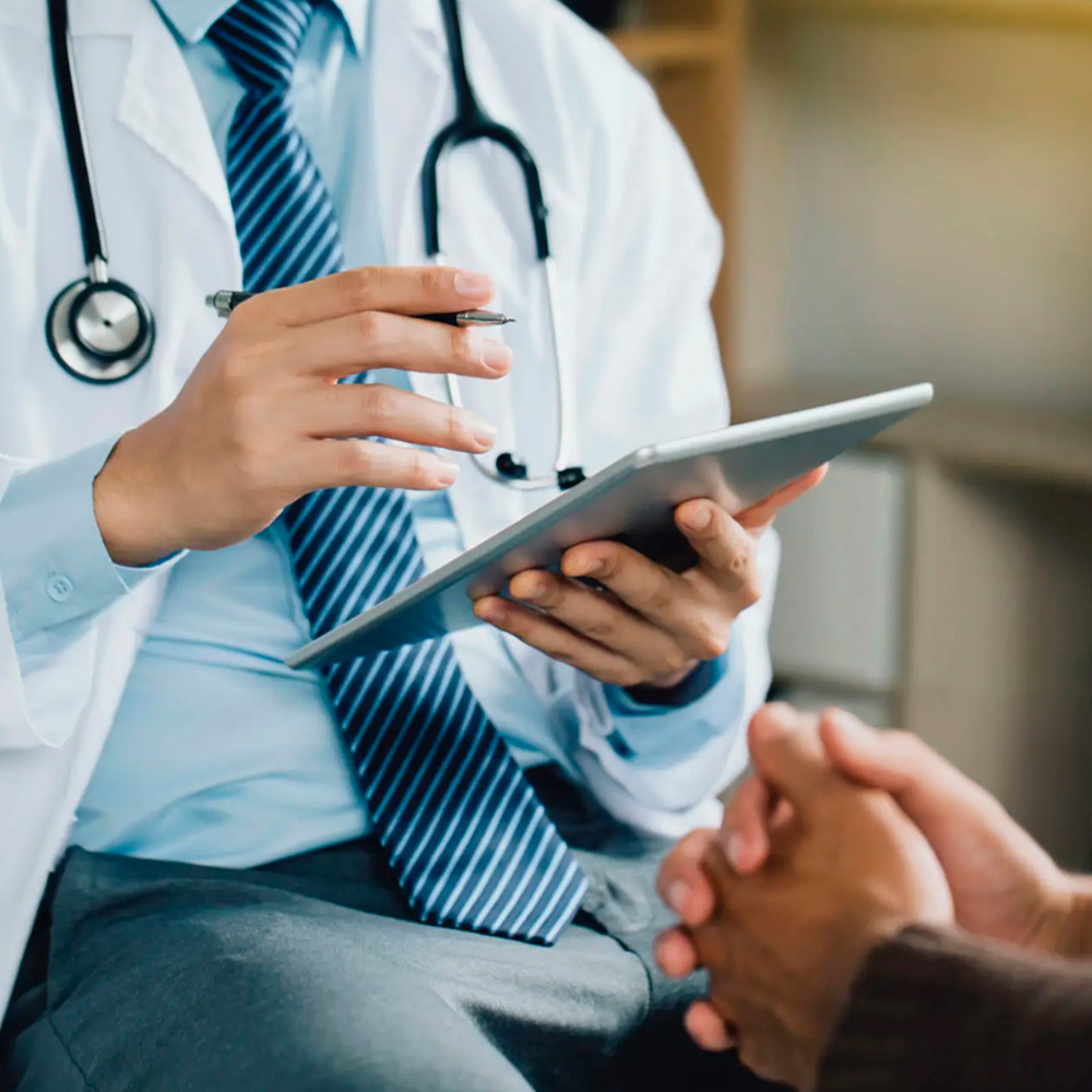 Doctor reviewing patient information on tablet during consultation.
