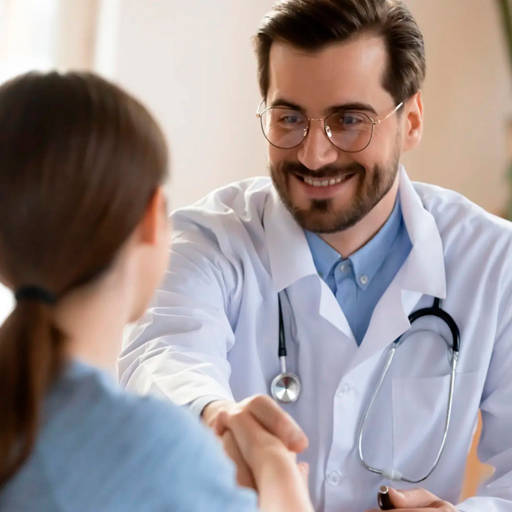 Smiling doctor greeting a patient during a consultation for migraine care.