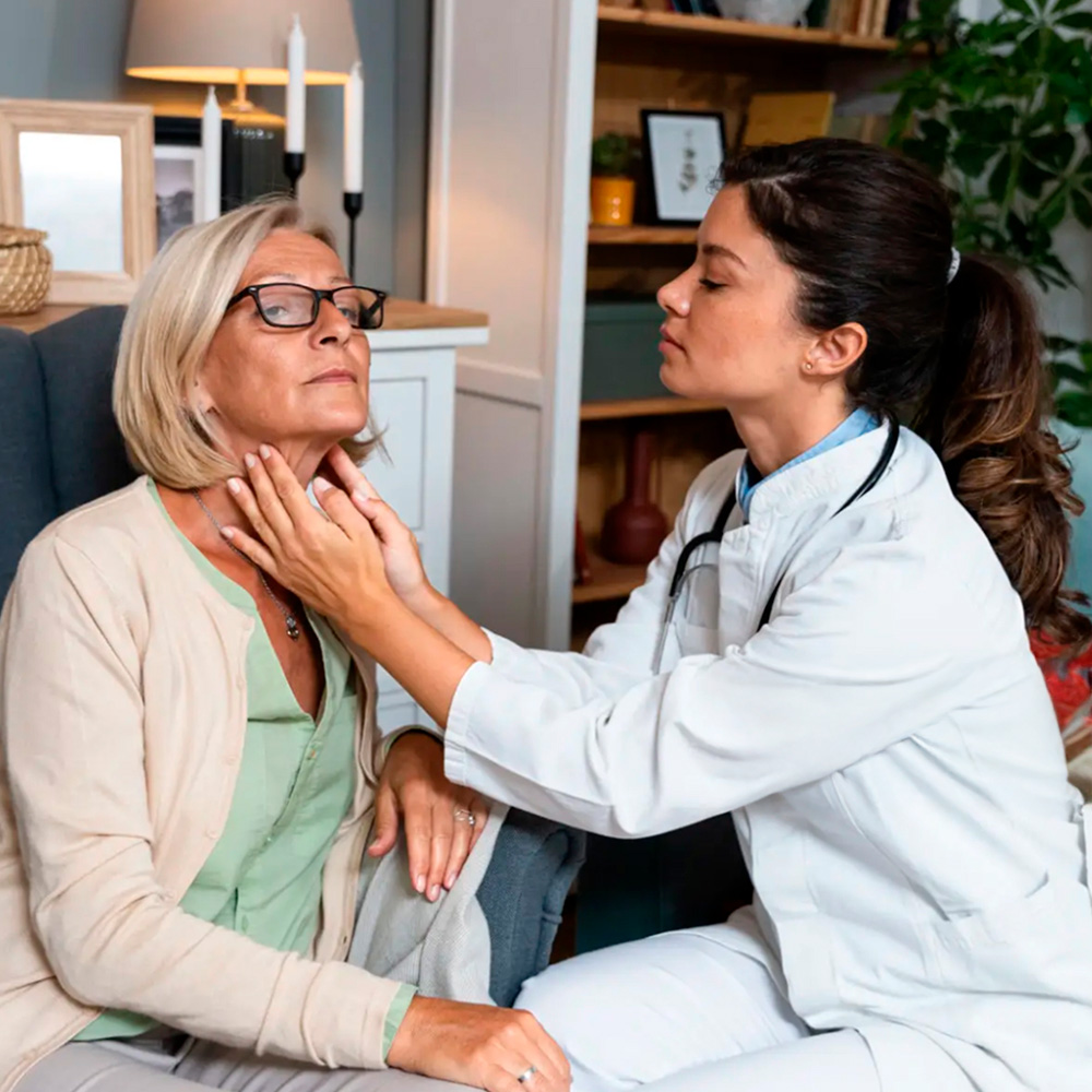 Doctor examining an older woman's neck for thyroid health.