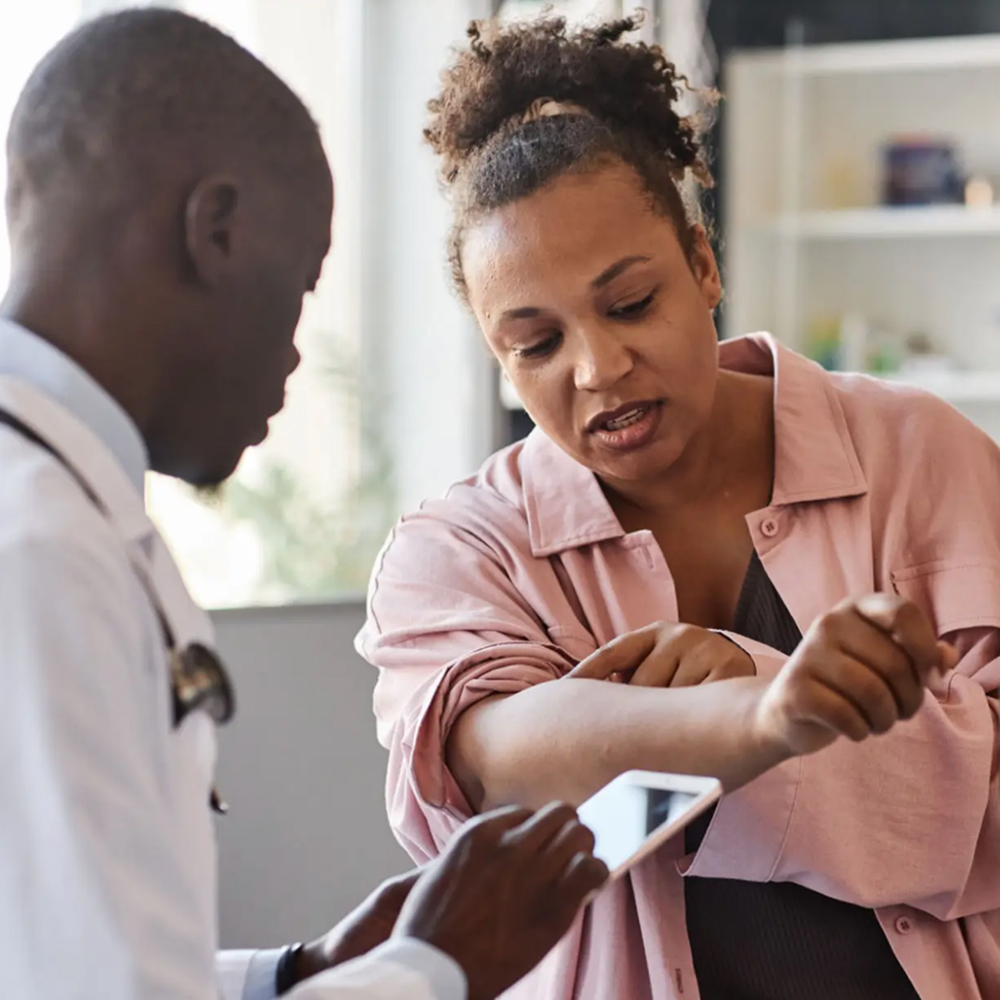 Patient showing skin rash to doctor during consultation.
