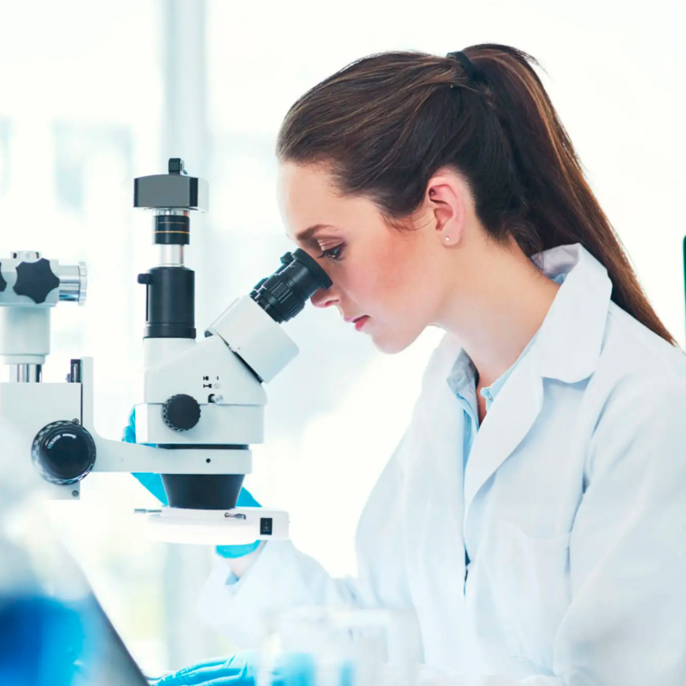 Lab specialist examining sample under microscope for yeast infection testing.