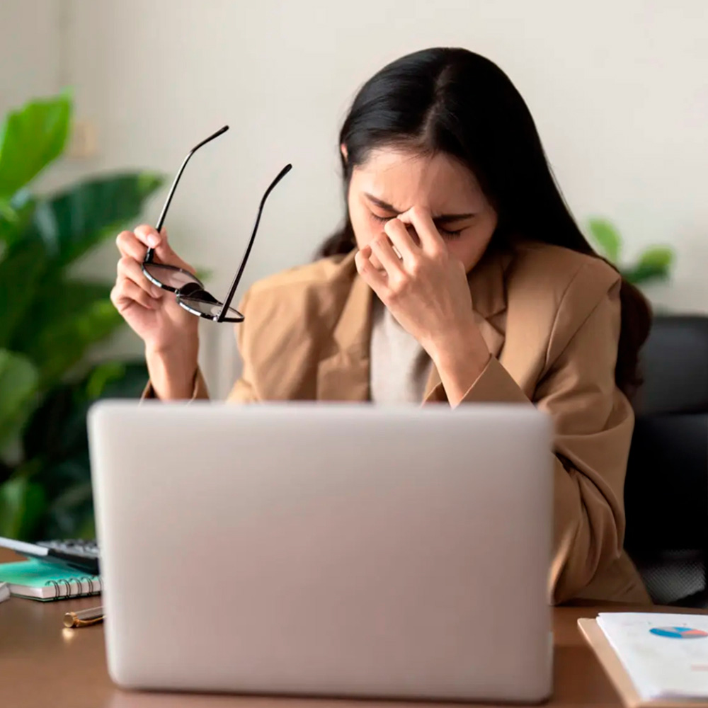 Woman experiencing fatigue or eye strain while working on a laptop.