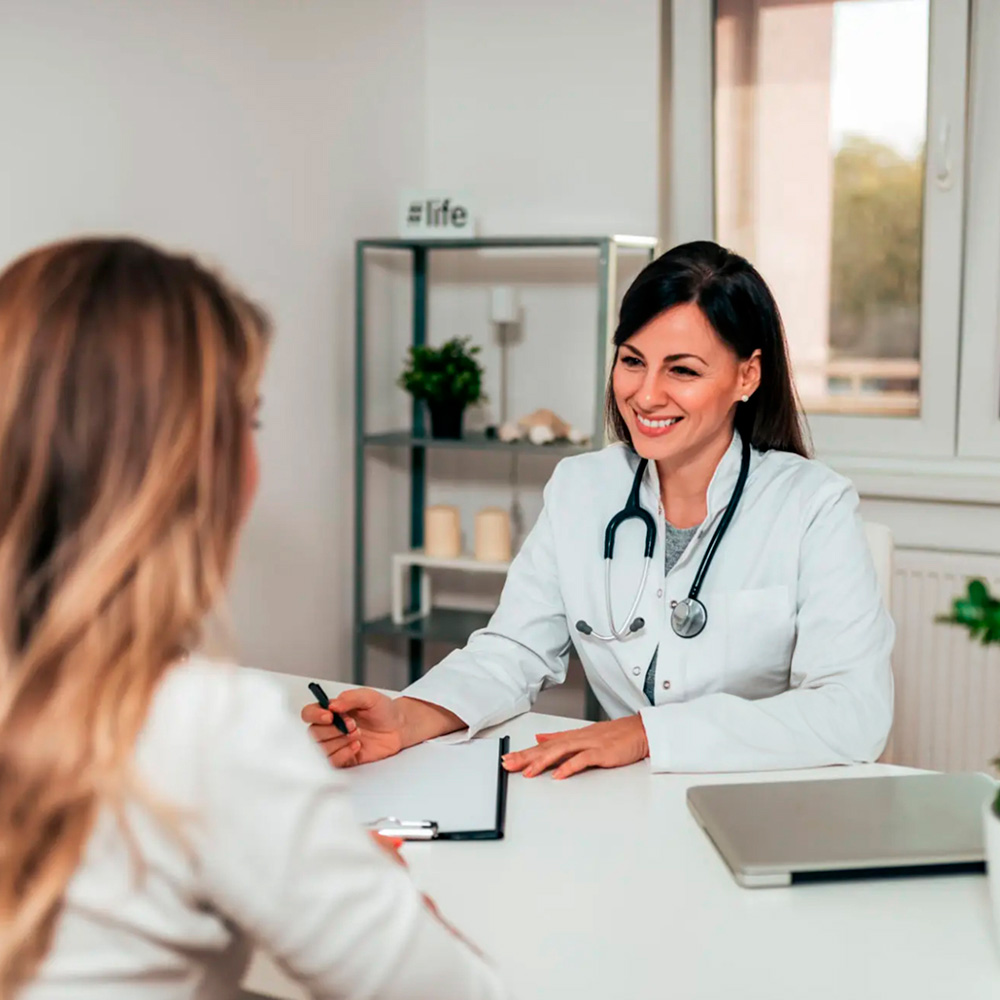 Female doctor smiling and consulting with a patient in a medical office.
